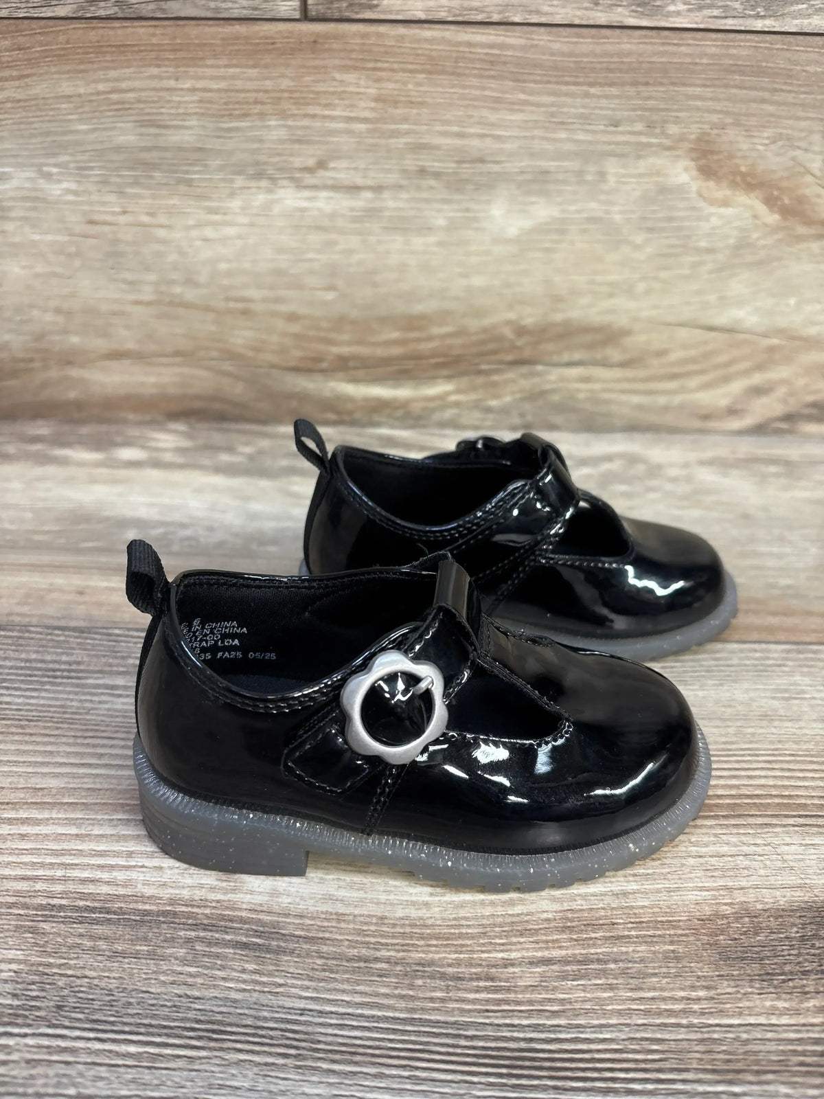 Angled view of Baby Gap T-Strap Loafers in black vegan patent leather with metal buckle and glitter detail