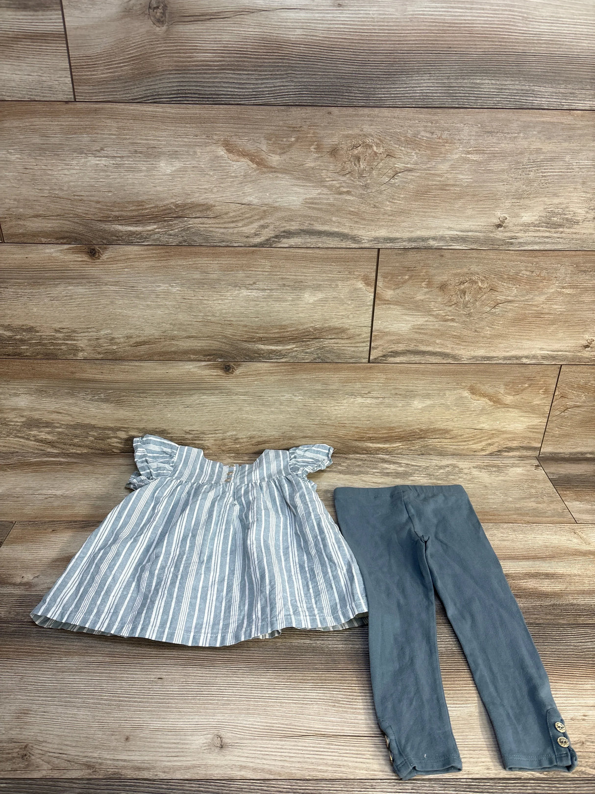 Striped ruffle sleeve toddler dress and gray leggings set on wooden background