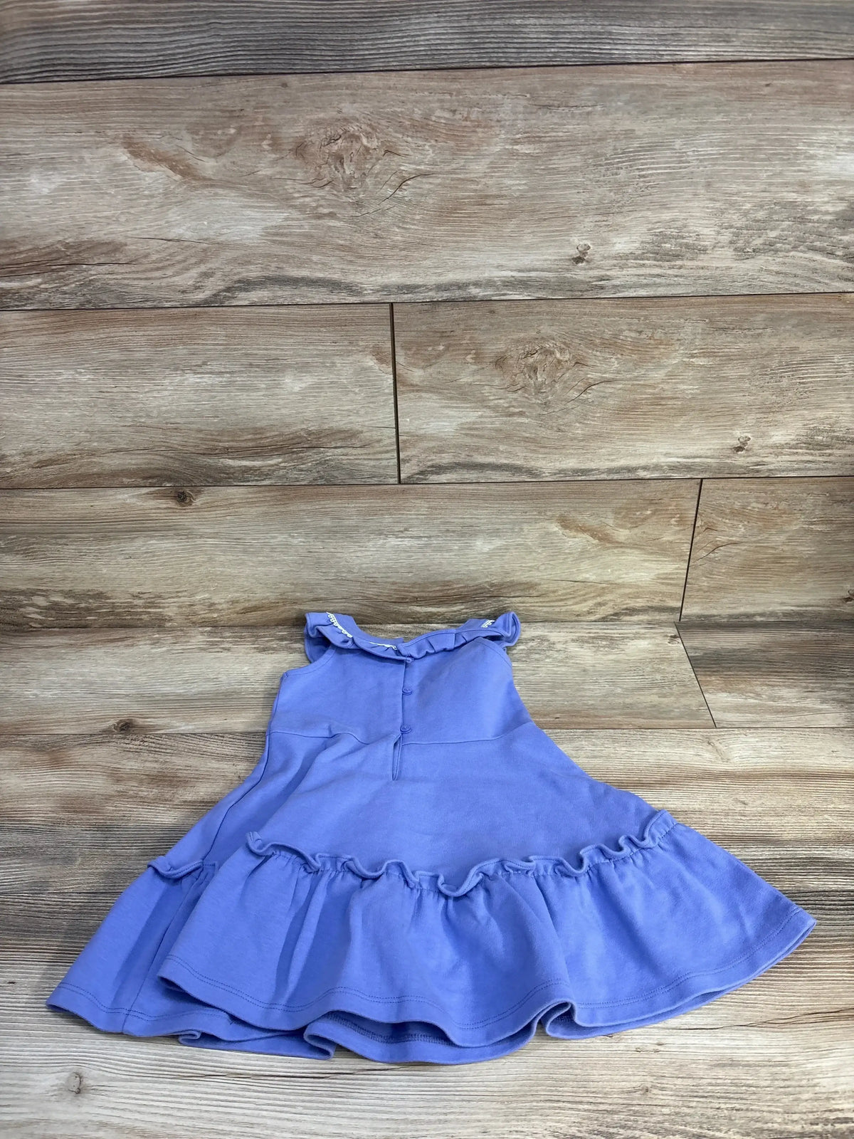Flat lay of girls Janie and Jack purple ponte dress showcasing circle-trim ruffle hem and ruffled collar on wood background