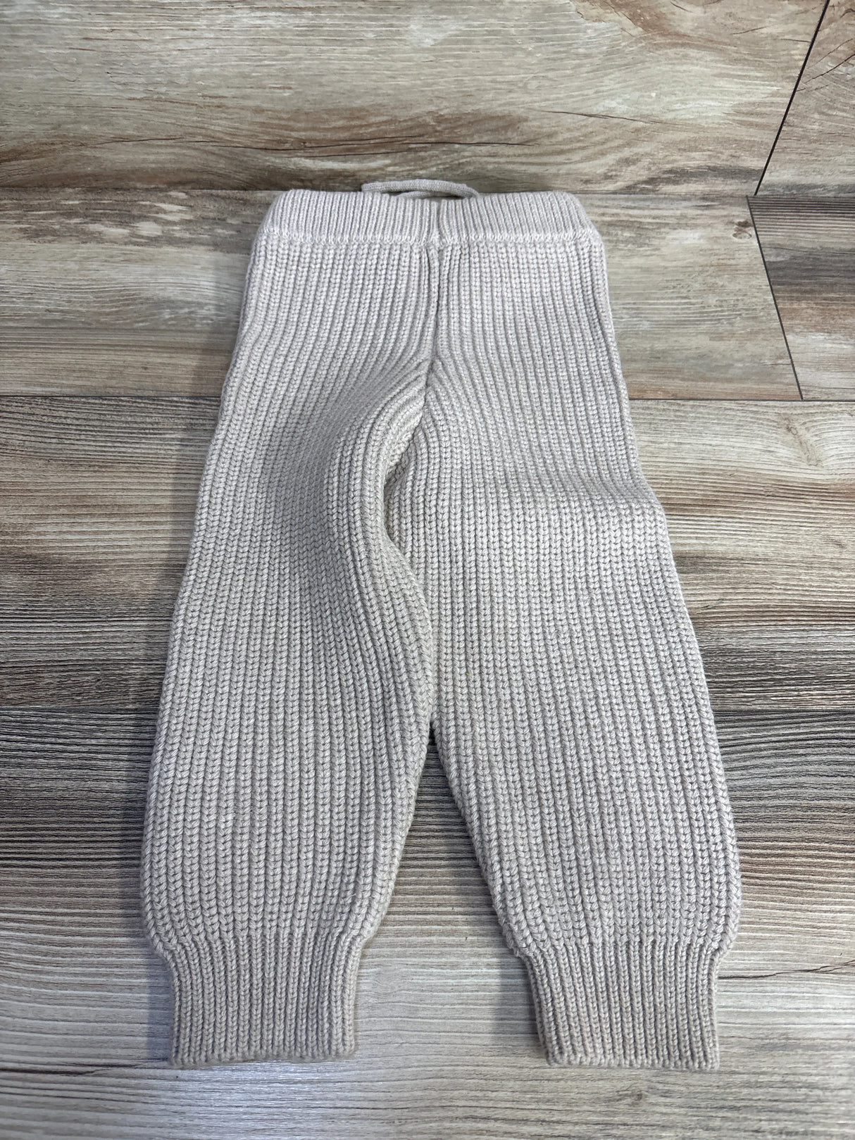 Light gray knit ribbed toddler pants on wood floor, used kids clothing