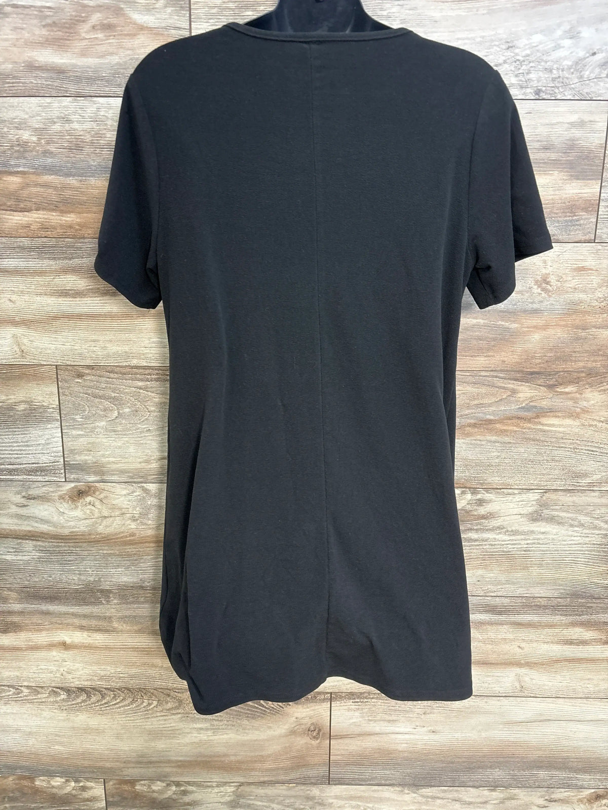 Back view of a black maternity nursing dress with short sleeves on a hanger against wood flooring