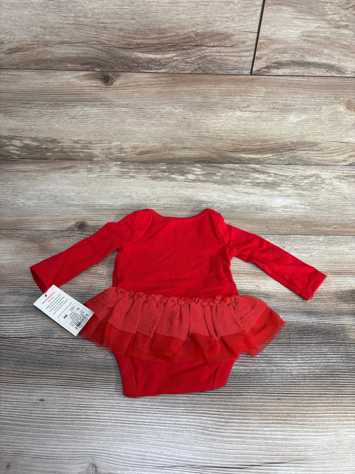 Red baby girl long sleeve bodysuit with tutu skirt displayed on wooden background