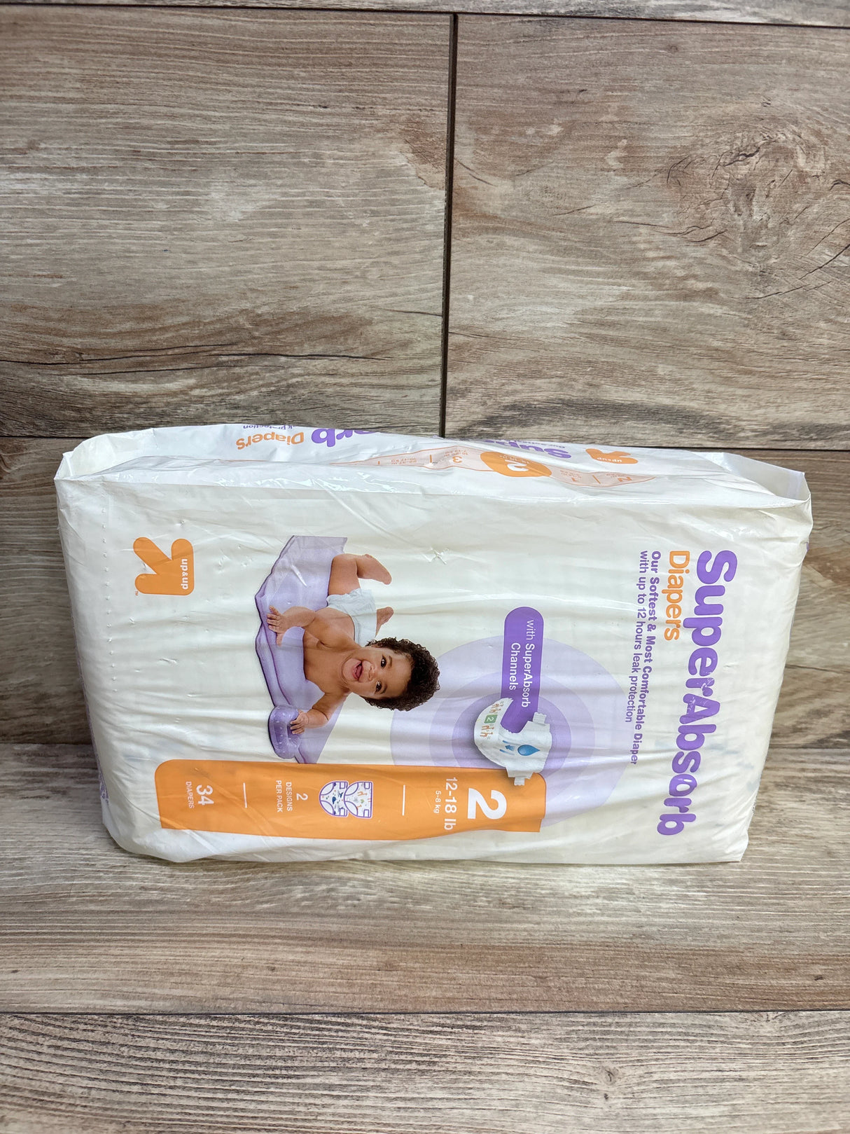 Package of SuperAbsorb size 2 baby diapers, 12-18 lb, 34 count, with image of smiling baby on wooden floor