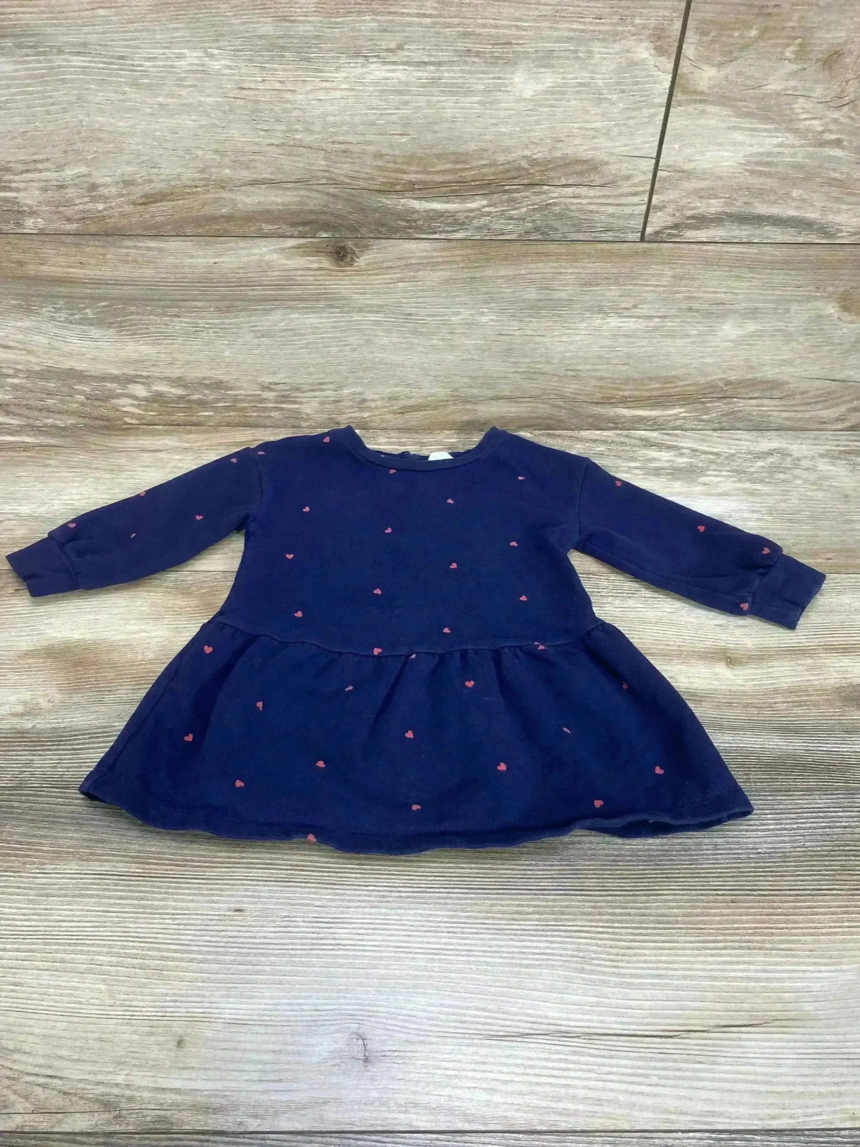 Flat lay of Baby Gap navy sweatshirt dress with pink heart print, long sleeves and gathered skirt on light wood background
