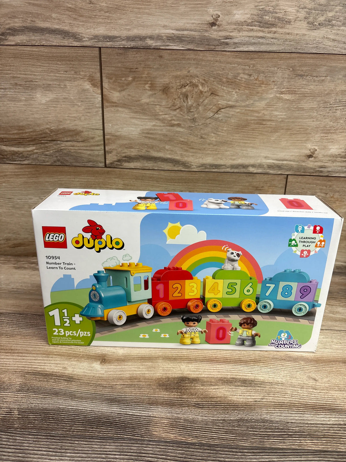 Front view of LEGO DUPLO Number Train toy box showcasing colorful numbered train cars and two figures on a wood surface