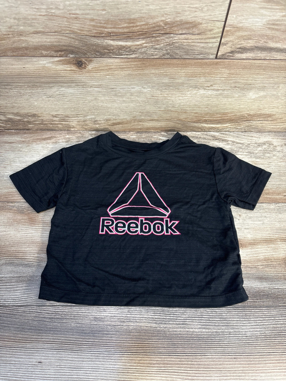 Black Reebok kids t-shirt with pink logo on wooden background, gently used clothing
