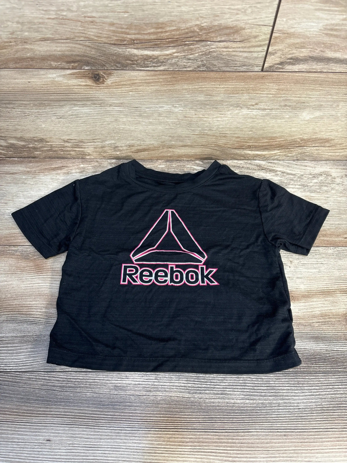 Black Reebok kids t-shirt with pink logo on wooden background, gently used clothing