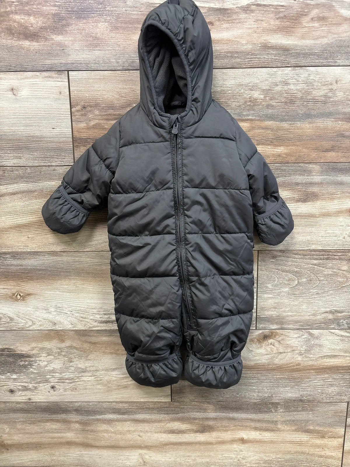 Front view of Baby Gap ColdControl Max snowsuit, grey hooded with zipper, mittens and foot cuffs on wood floor, 3-6m