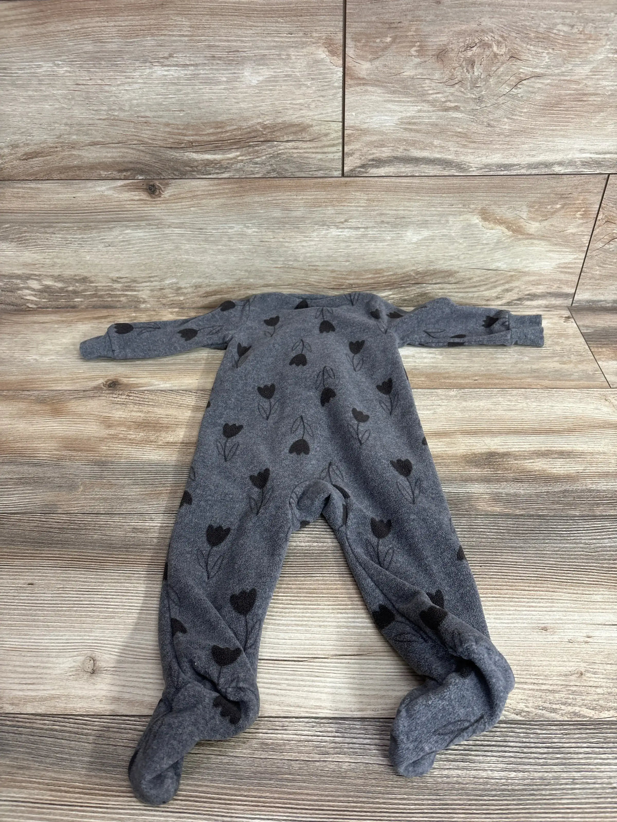 Flat lay of Carter’s grey footed coverall showing black tulip print and enclosed feet on light wood background