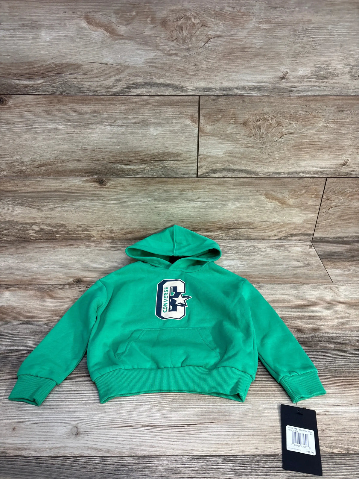 Green Converse kids hoodie with front logo and tag on wooden floor background