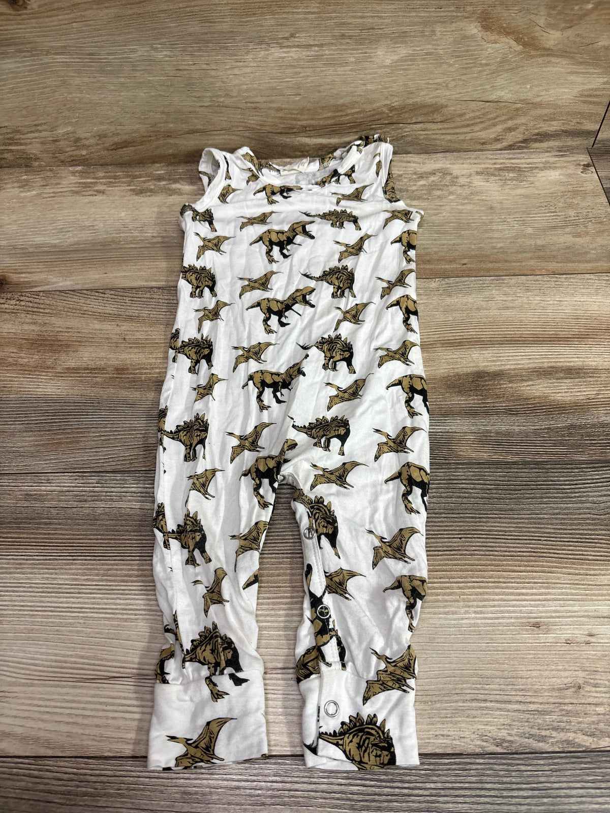 Kate Quinn white bamboo sleeveless dinosaur jumpsuit for infants on a wooden background