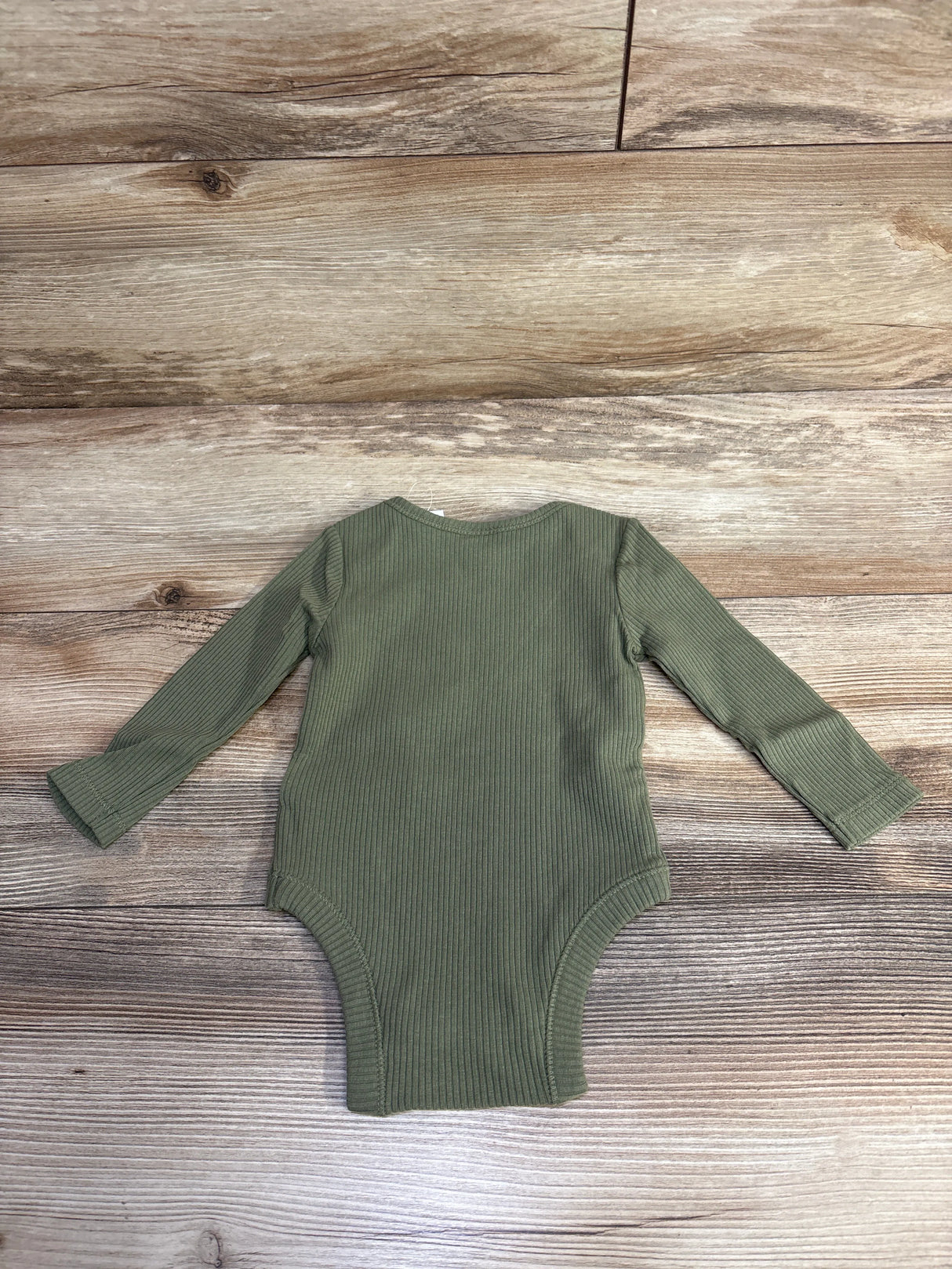Olive green ribbed long sleeve baby bodysuit on wooden background