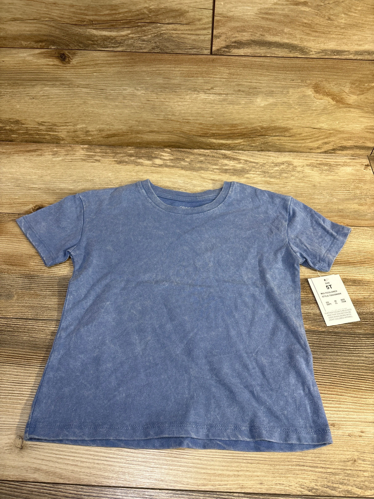 Front view of blue Grayson Mini short-sleeve children’s T-shirt with crew neck and faded wash on wood background, size 5T tag visible