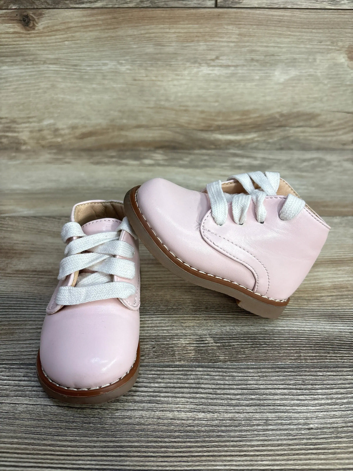 Front and side view of Josmo First Walker pink ankle shoes size 4.5C showcasing white laces and stitched brown sole on wood surface