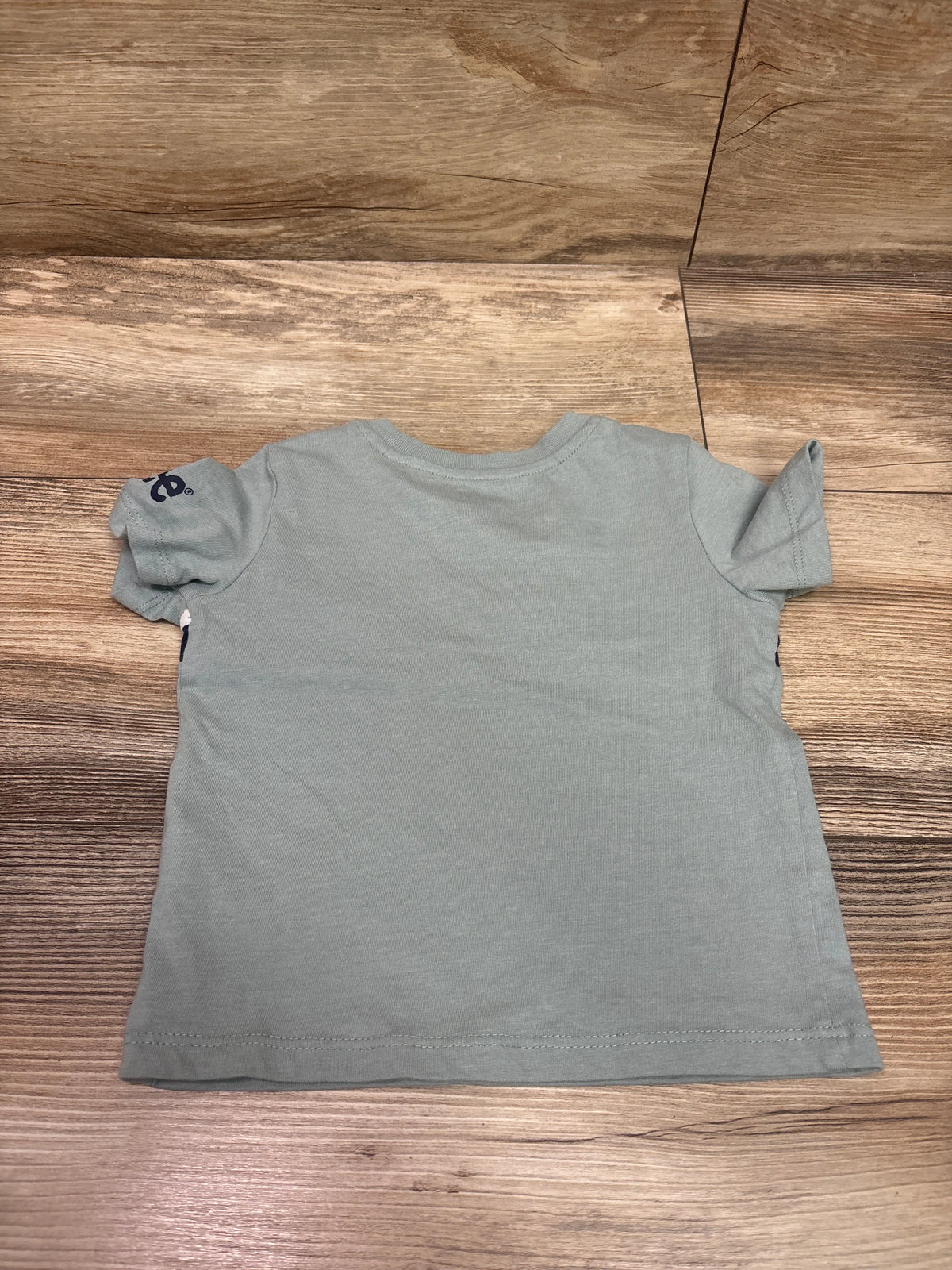 Front view of Lee green shirt in size 18m with short sleeves and a small dark emblem on the left sleeve displayed on a wood floor