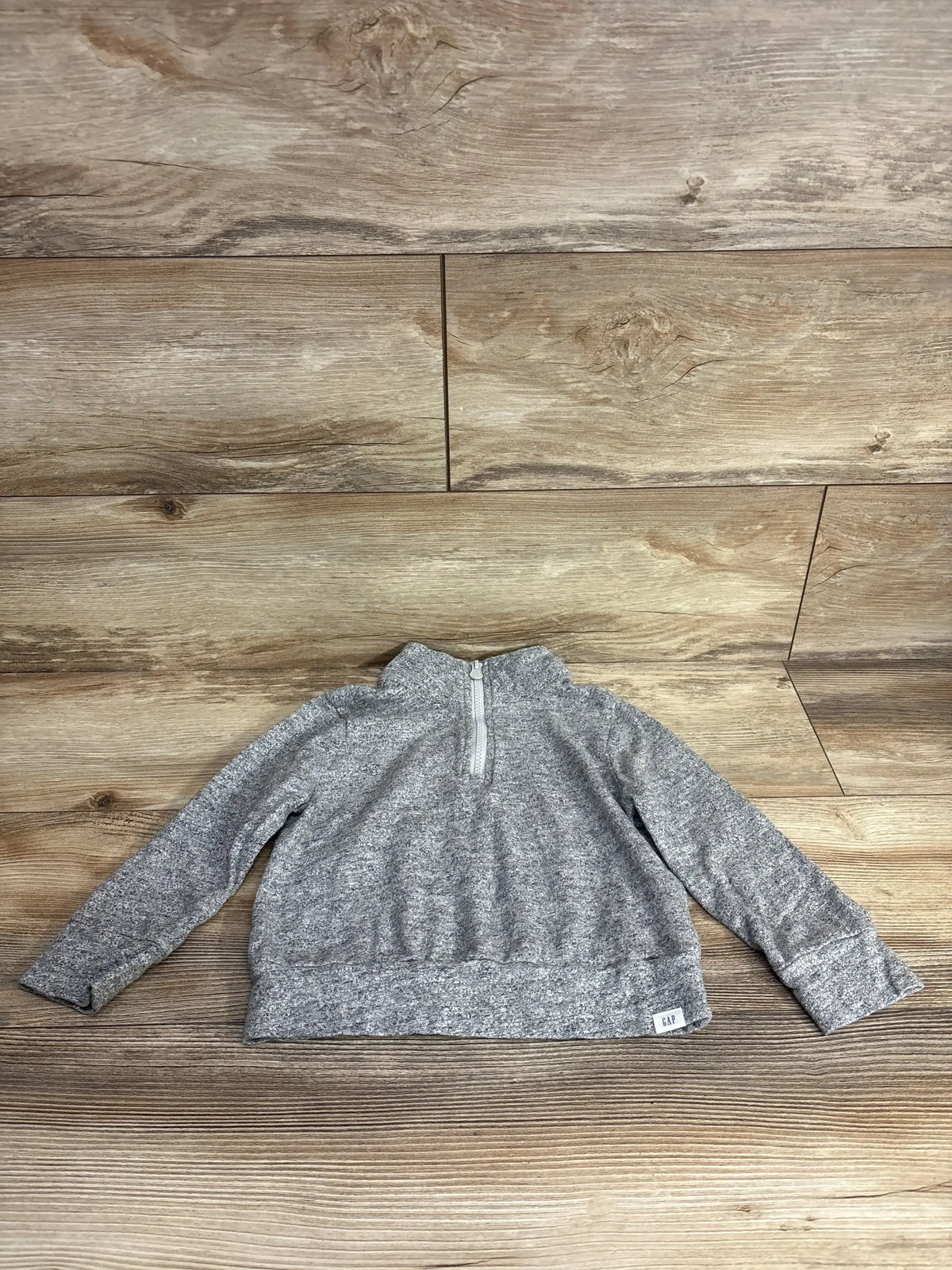 Kids grey long sleeve quarter-zip sweater with GAP label, laid flat on wood background