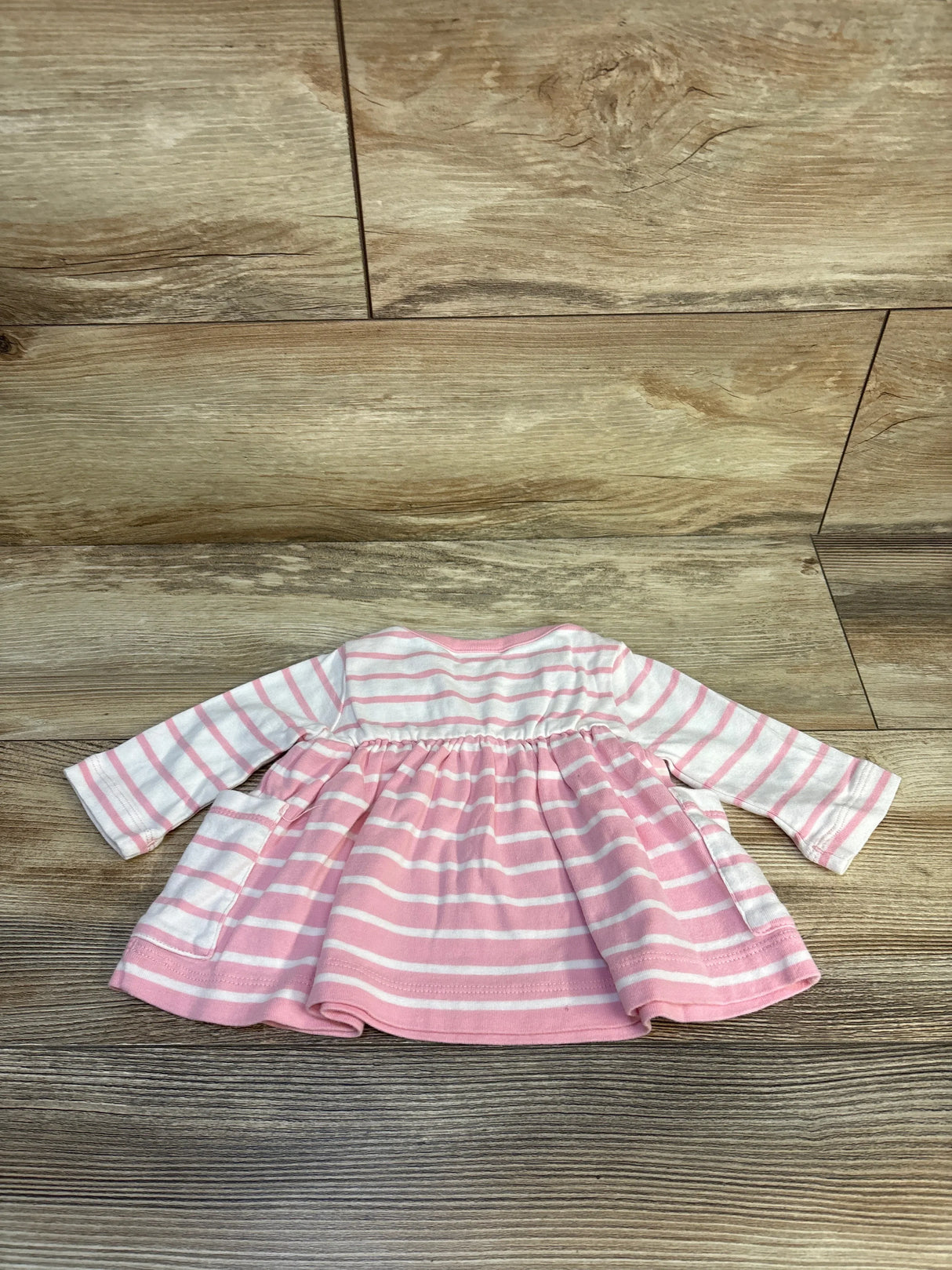 Pink and white striped long sleeve baby dress on wood background