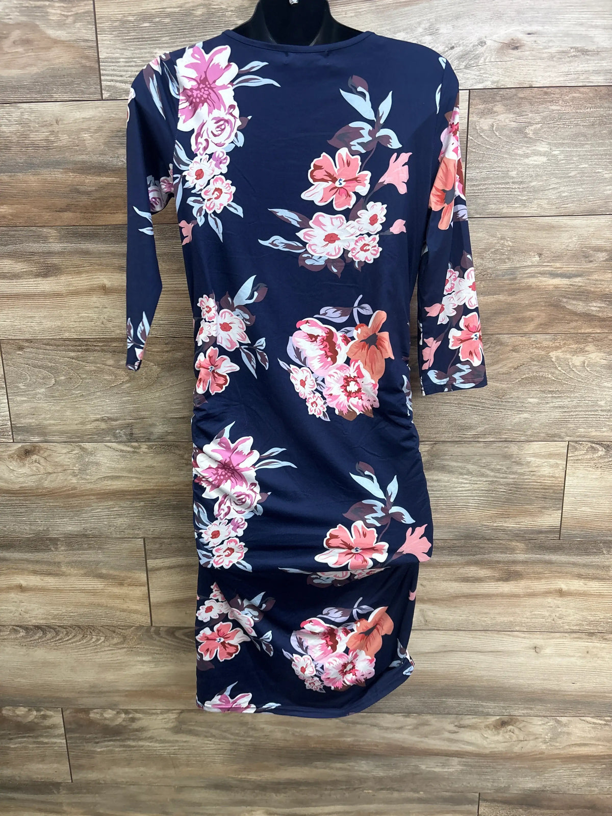 Front view of Miss Qee maternity floral bodycon dress in navy showcasing long sleeves on a wooden floor