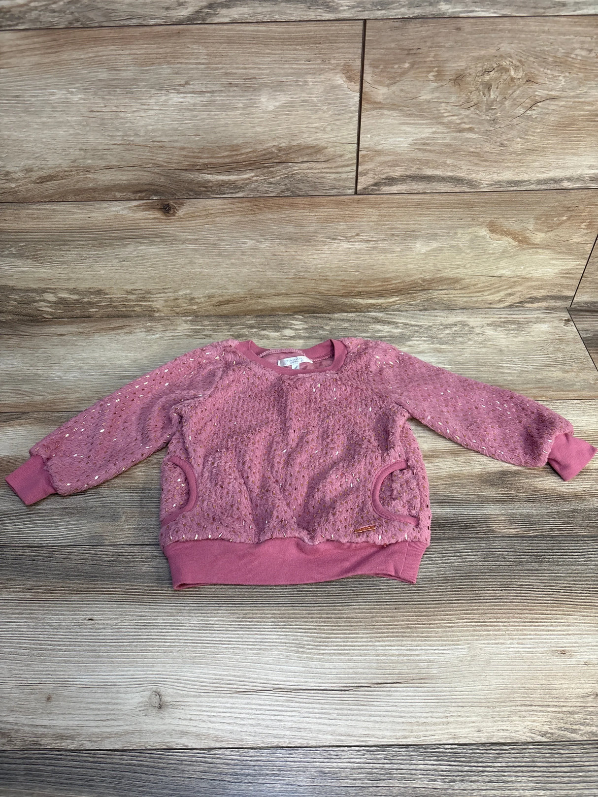 Pink toddler sweater with textured knit, long sleeves, and sequin details on wooden floor