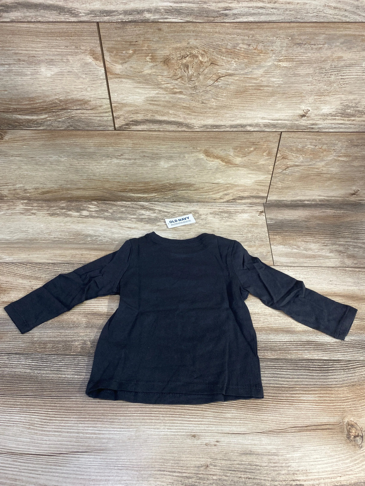 Back view of Old Navy Hide And Seek Champion grey shirt, size 12 to 18 months, showcasing long sleeves on a wood floor