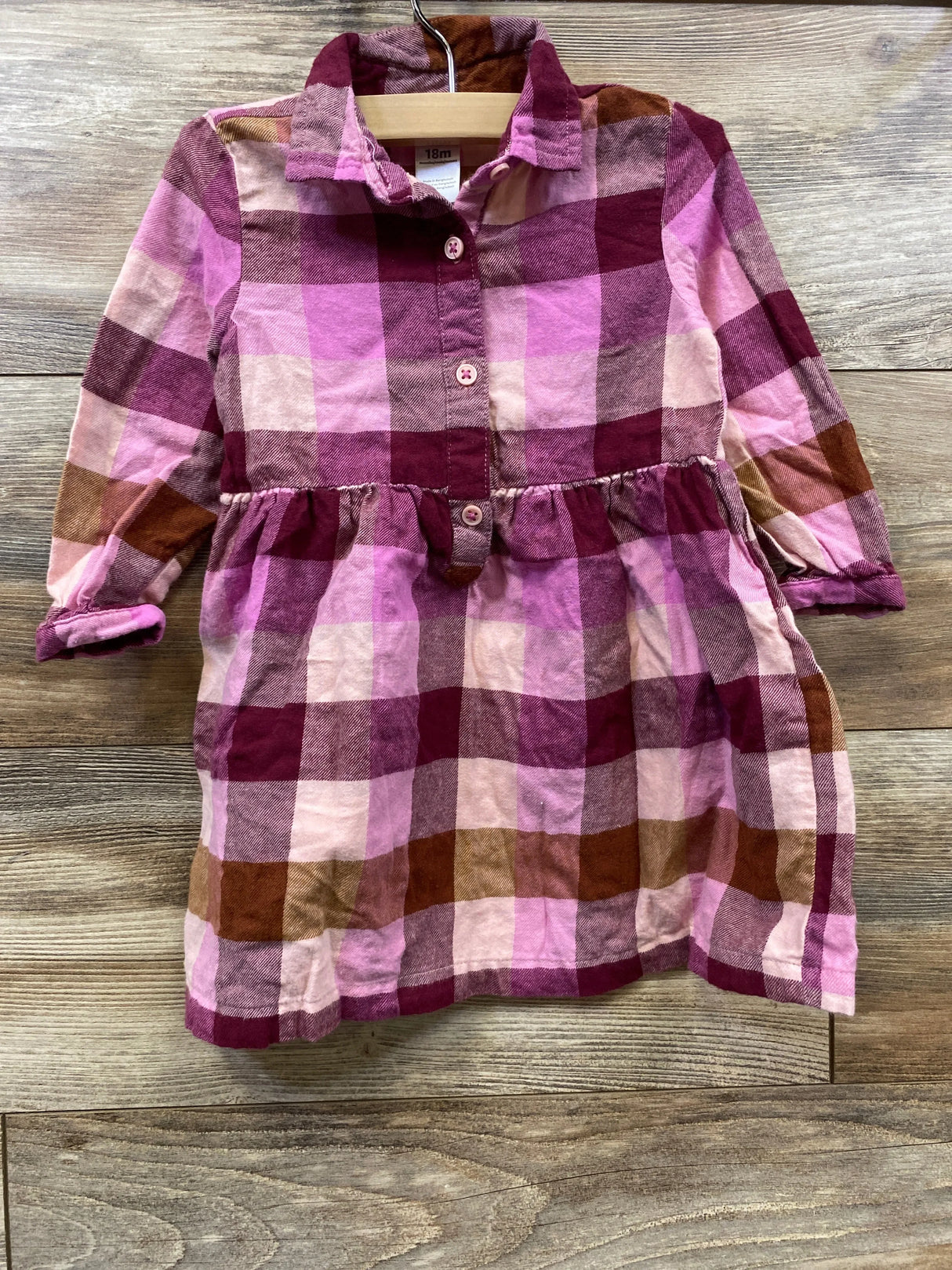Plaid long sleeve toddler dress in pink, burgundy, and brown on wooden background