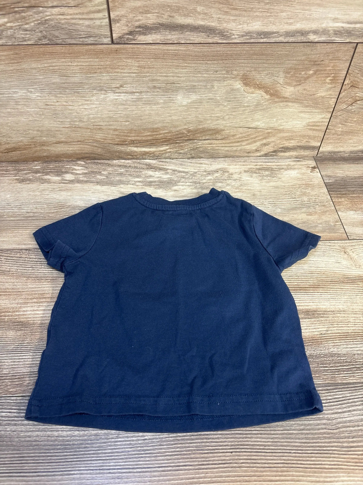 Navy blue toddler t-shirt laid flat on wood floor, kids clothing resale