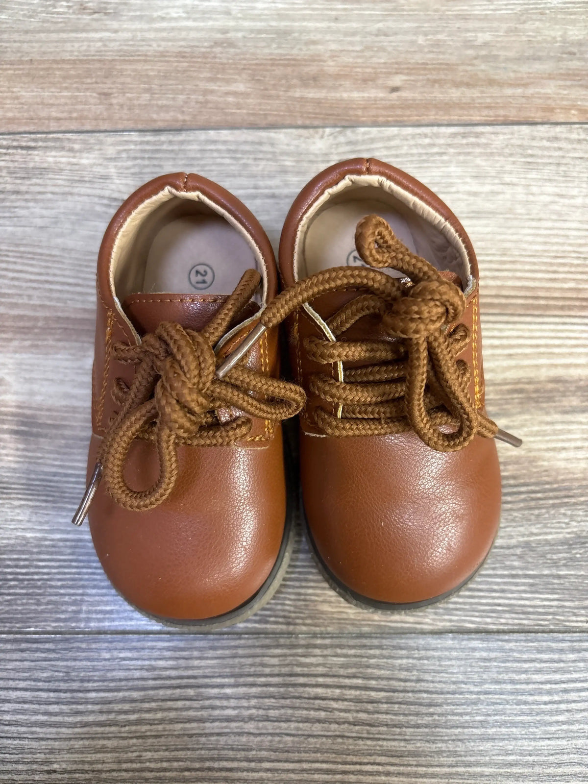 Top view of brown Meckior Oxford dress shoes showcasing lace-up closure and PU leather with wood-grain background