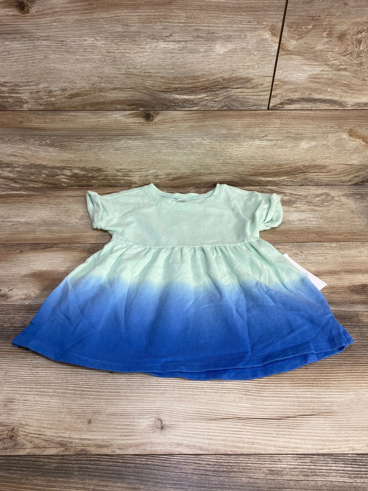 Flat lay of Old Navy toddler ombre tunic (4T) showing mint-to-blue gradient skirt, short sleeves, and gathered waist on wood background