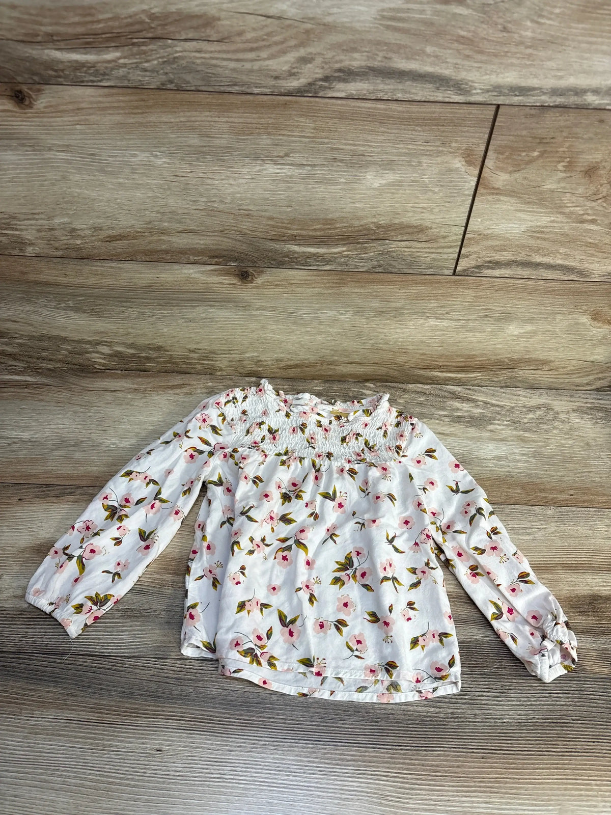 White floral long sleeve baby top with smocked neckline, perfect for kids' spring outfits