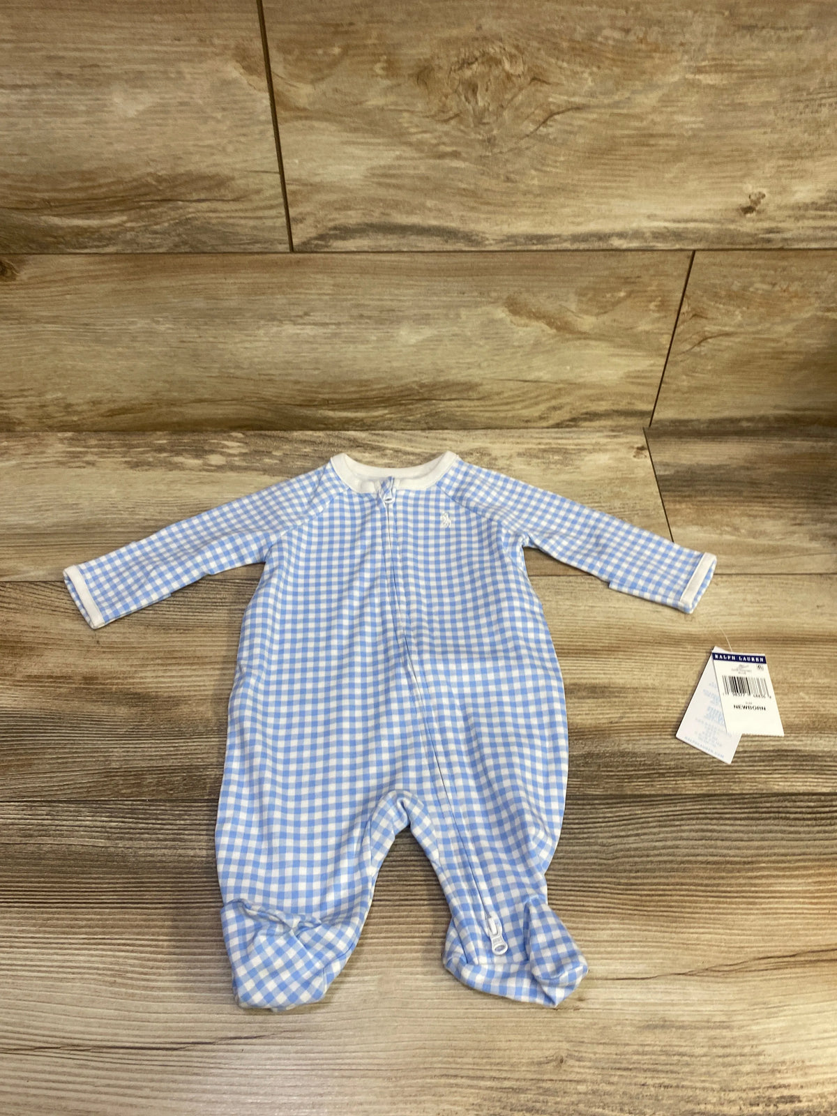 Front view of a blue gingham Ralph Lauren newborn footie sleeper with long sleeves, front zipper and covered feet on wood floor