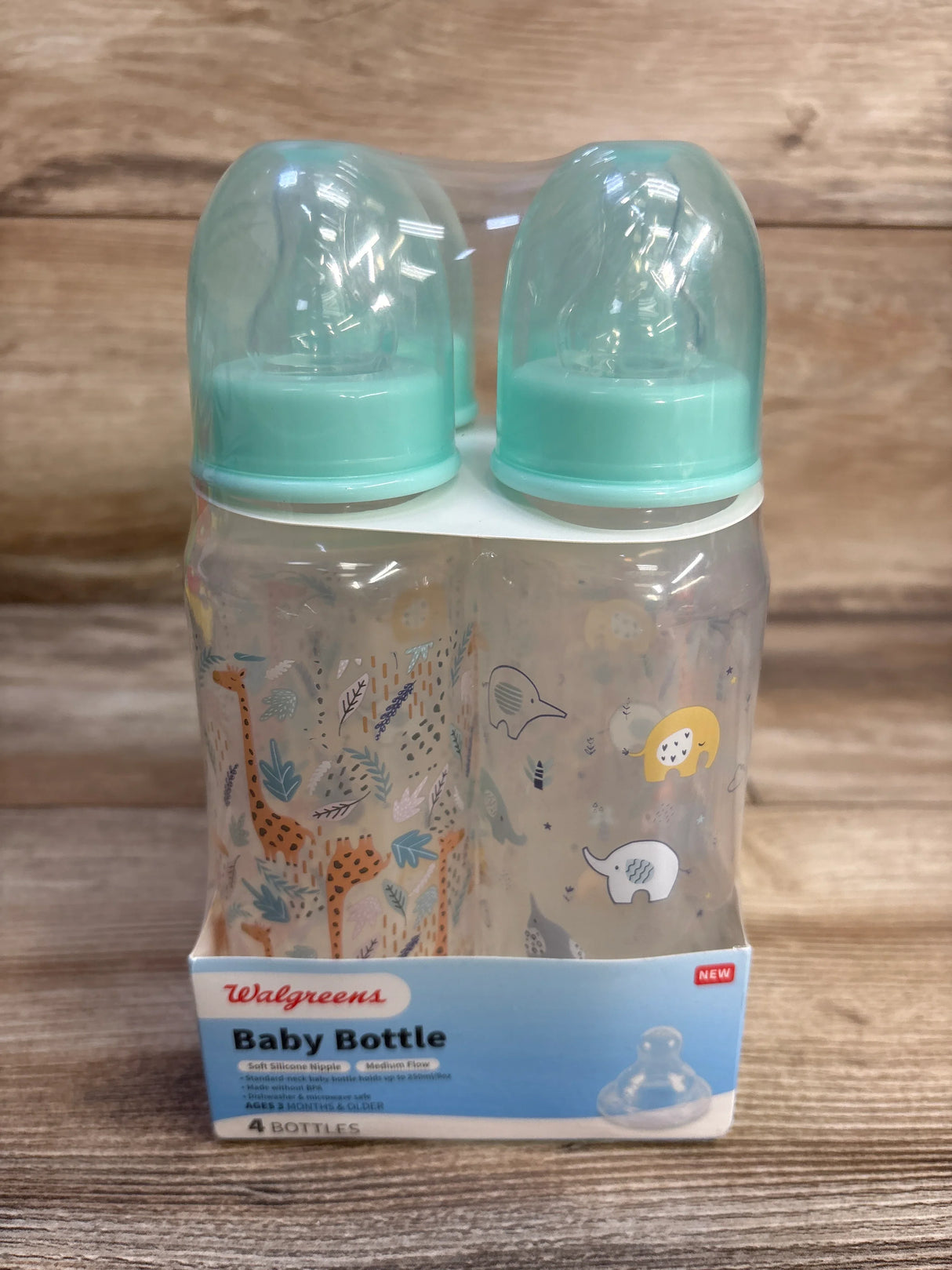 Front view of Walgreens 4-pack baby bottles showing mint green caps and animal-print bottles on wood background