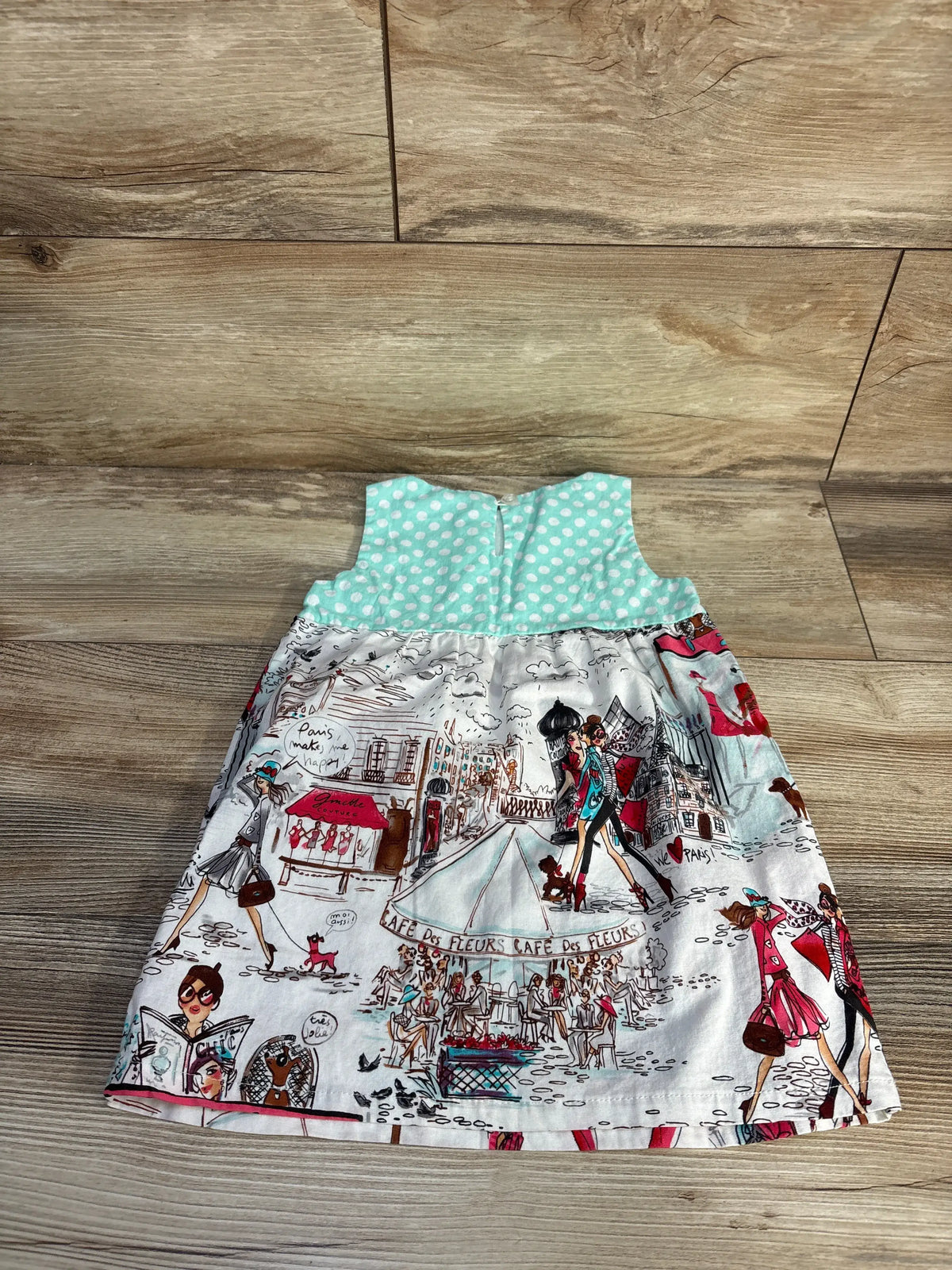 Front view of Wonder Me Paris blue sleeveless dress showcasing polka-dot bodice and Paris print skirt on wood floor