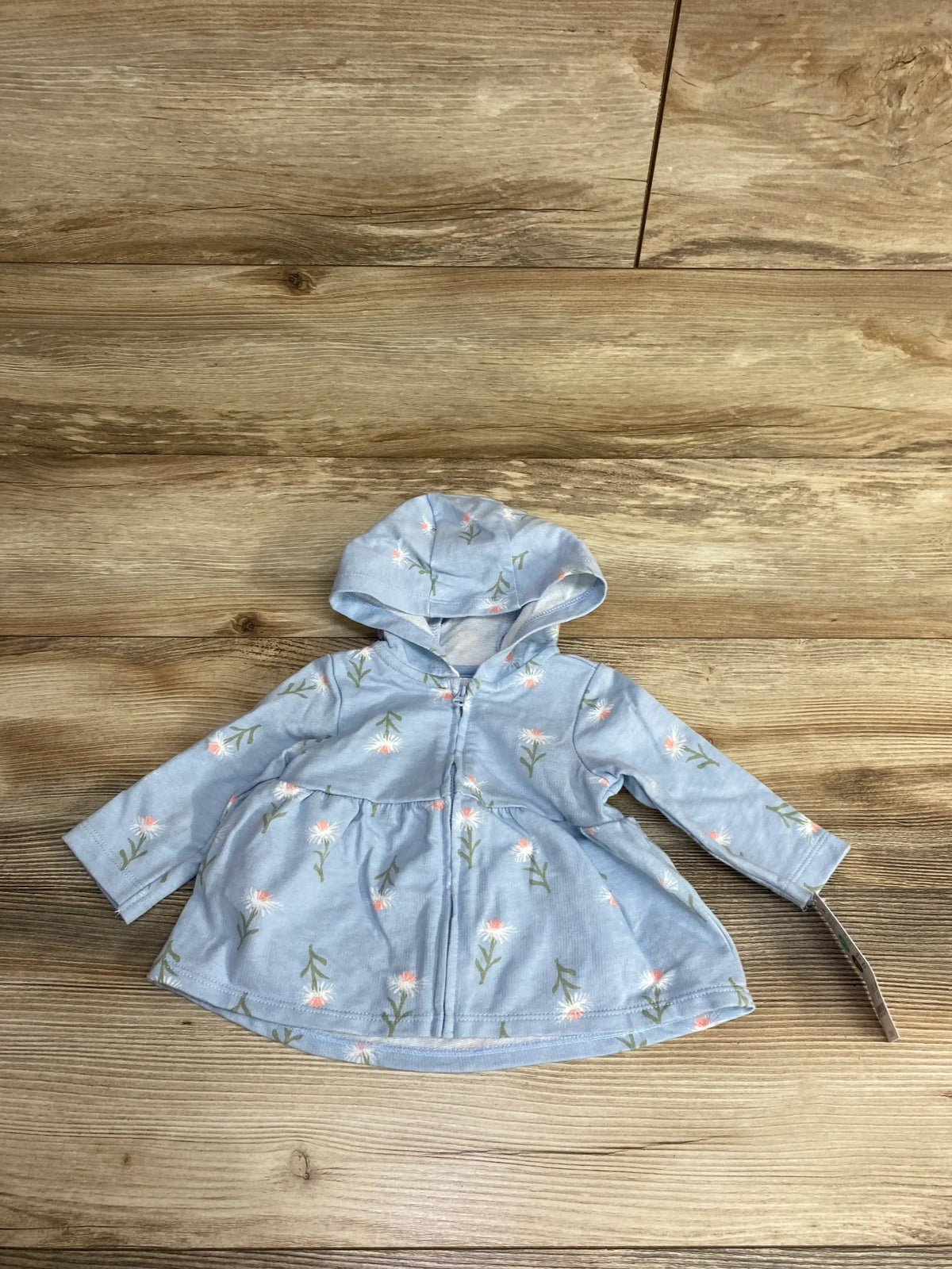 Light blue baby hoodie with pink and white floral print laid flat on wood floor, children's clothing