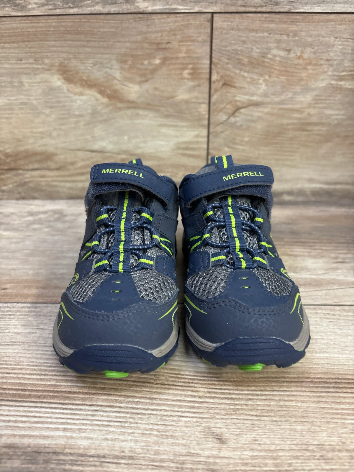 Front view of Merrell Trail Chaser hiking sneakers in navy with lime accents, mesh panels, and hook-and-loop straps on wood flooring