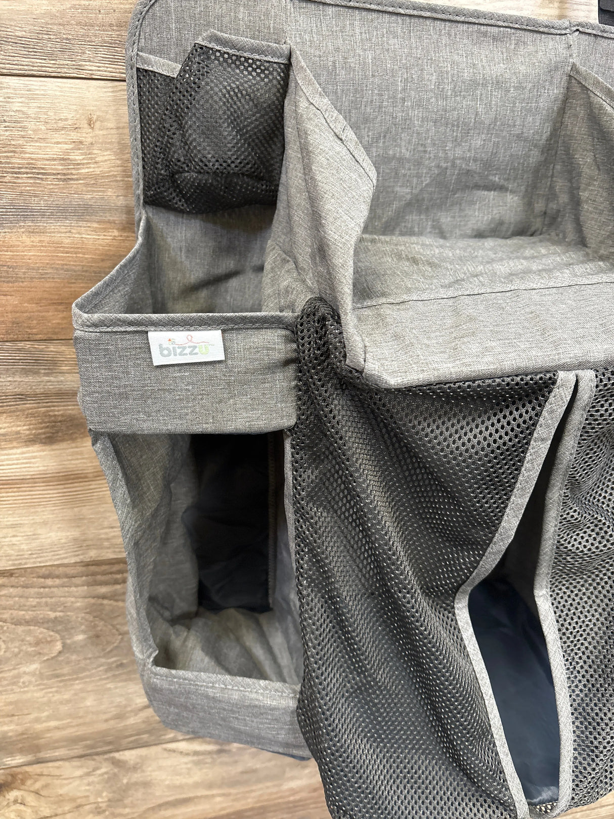 Gray fabric and mesh diaper caddy organizer with multiple compartments on wood background