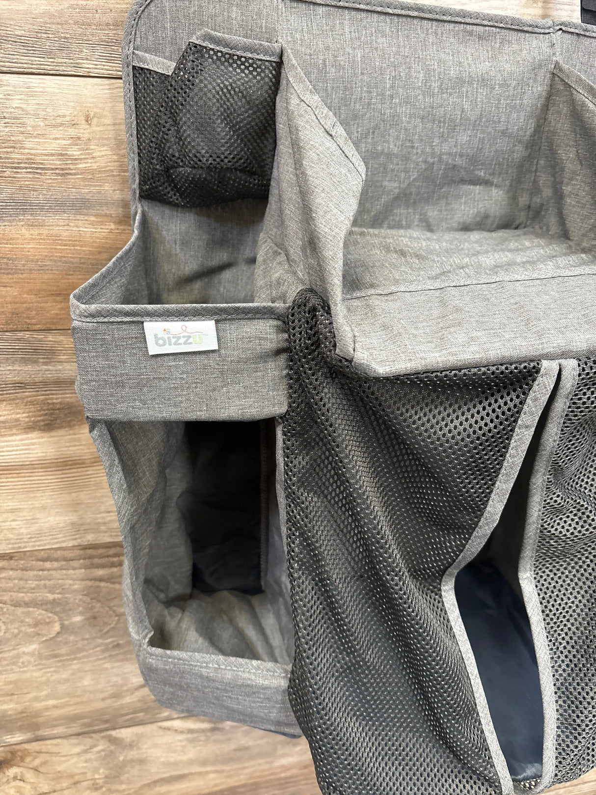 Gray fabric and mesh diaper caddy organizer with multiple compartments on wood background