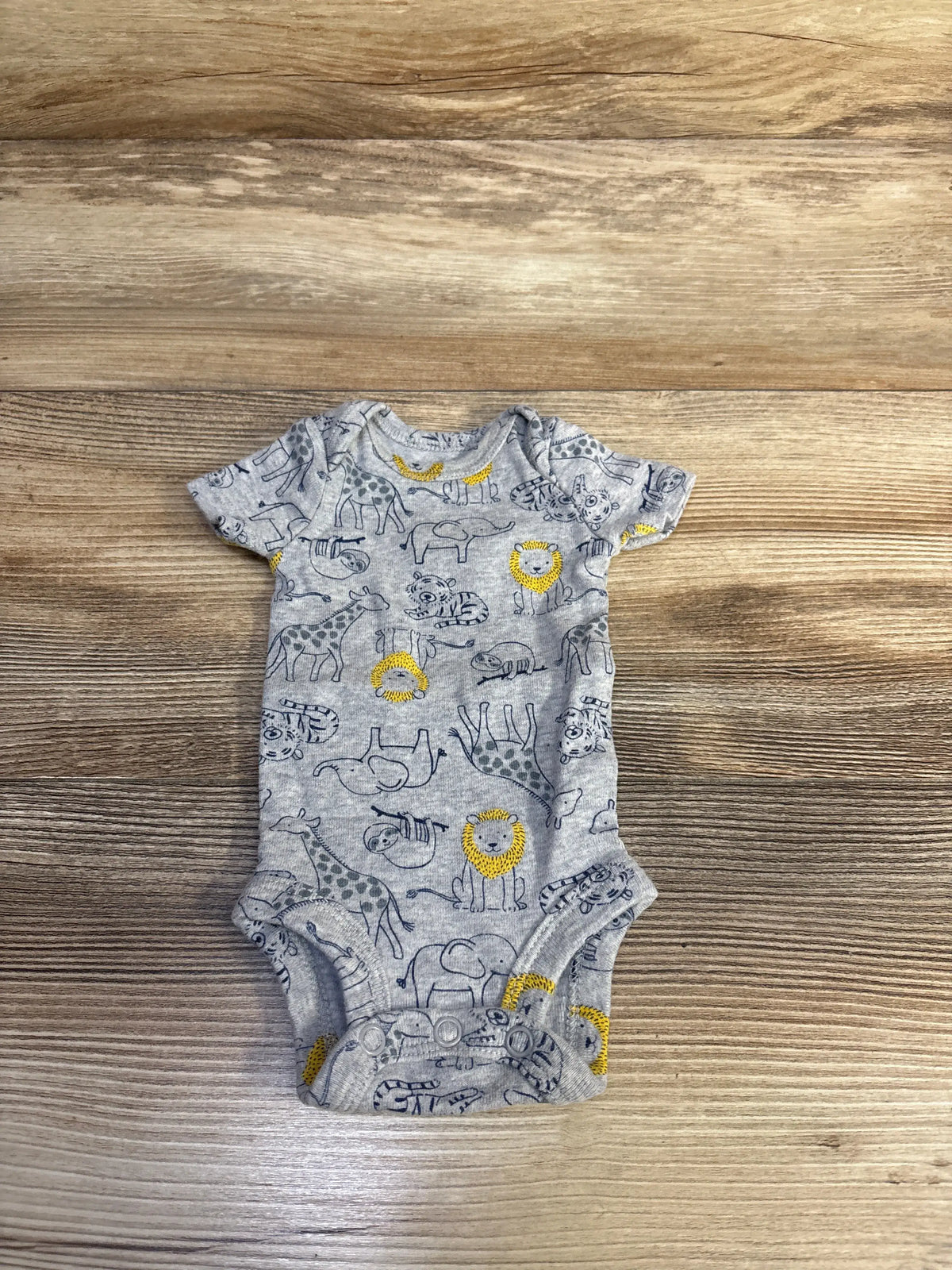 Front view of Child of Mine grey preemie bodysuit showcasing animal print, short sleeves, and snap closure on wood background