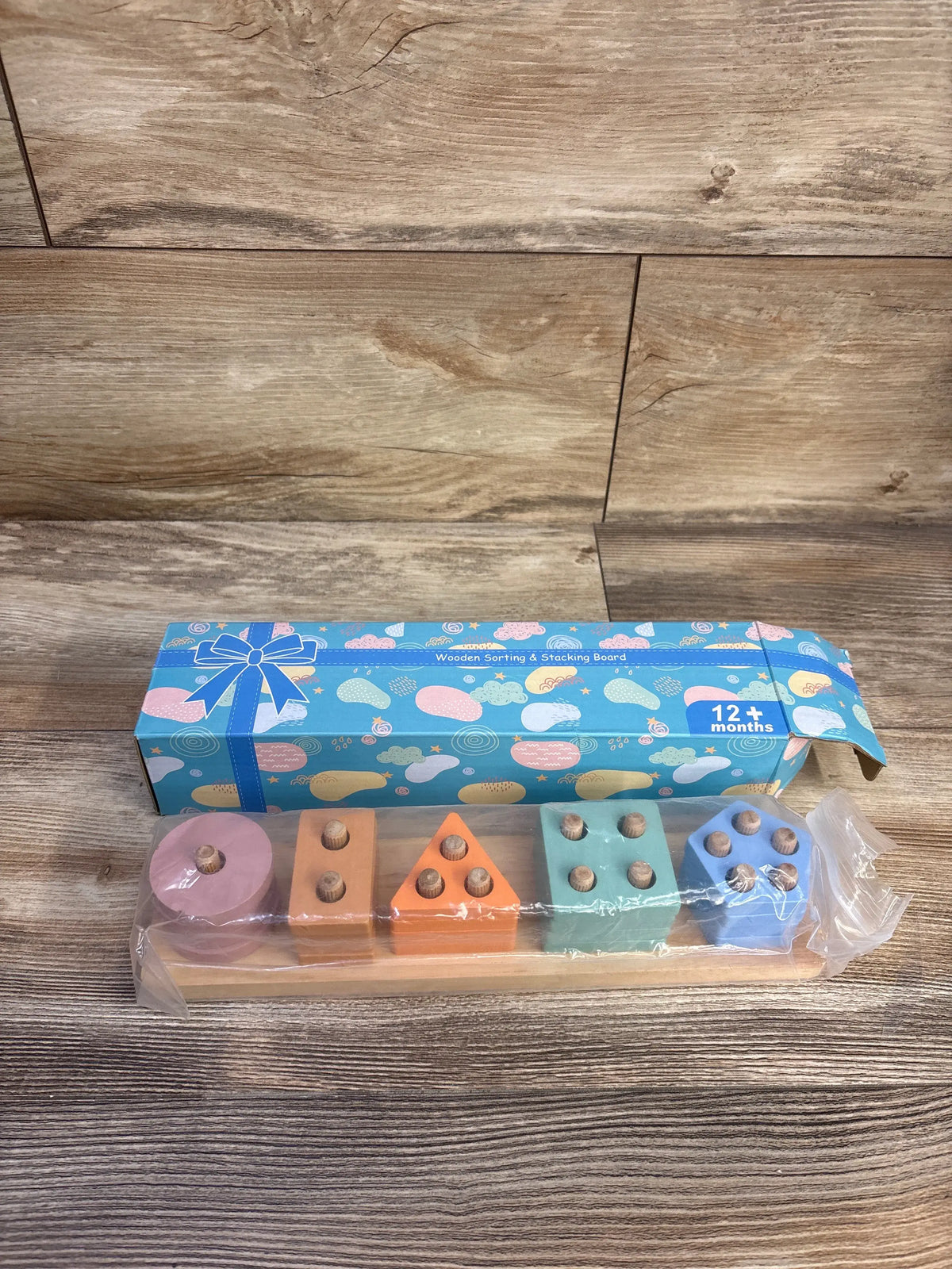 Front view of HelloWood Montessori sorting and stacking board with colorful wooden shape blocks and packaging