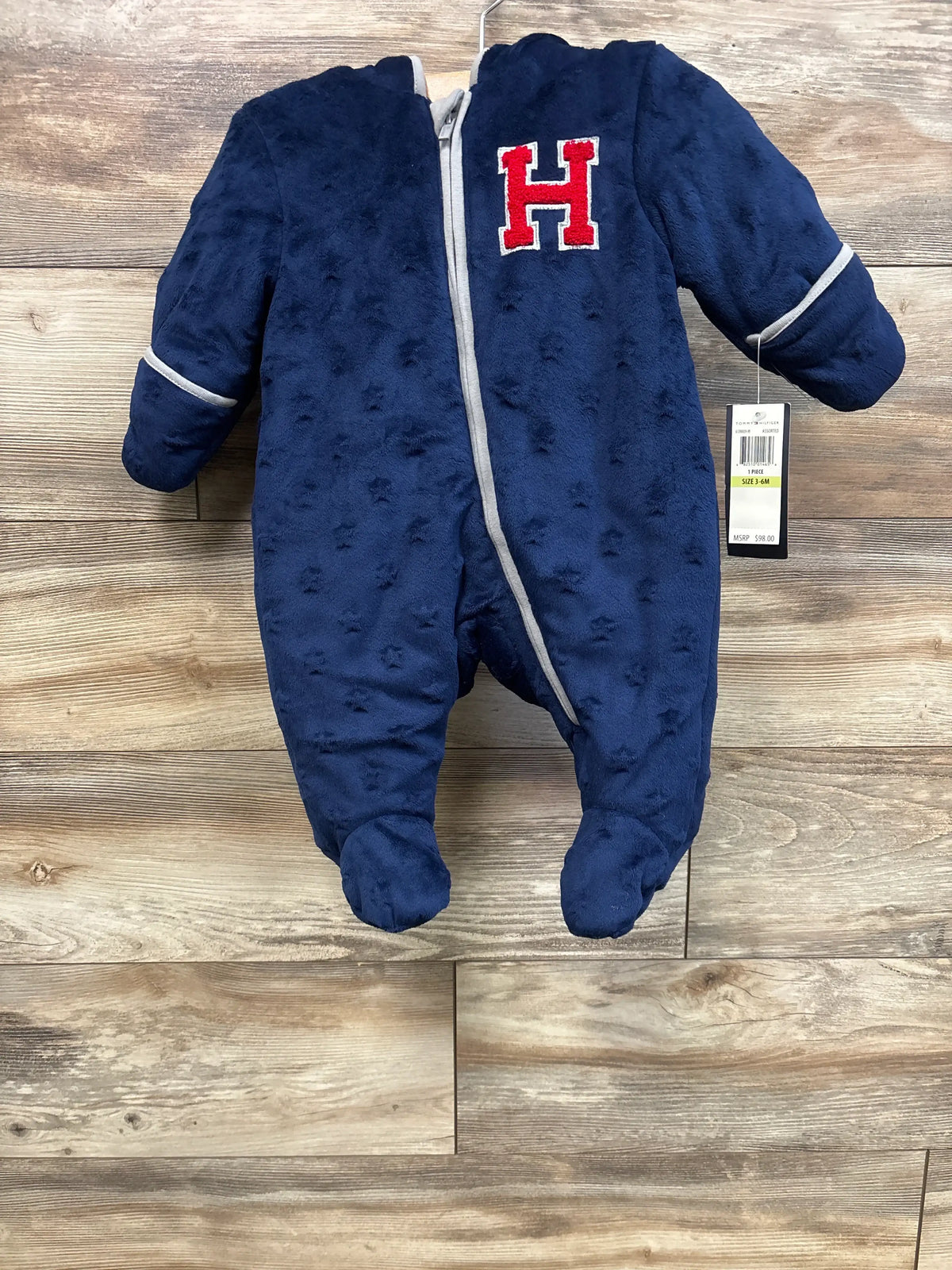 New blue Tommy Hilfiger hooded fleece bunting for babies size 3-6m on a wooden wall