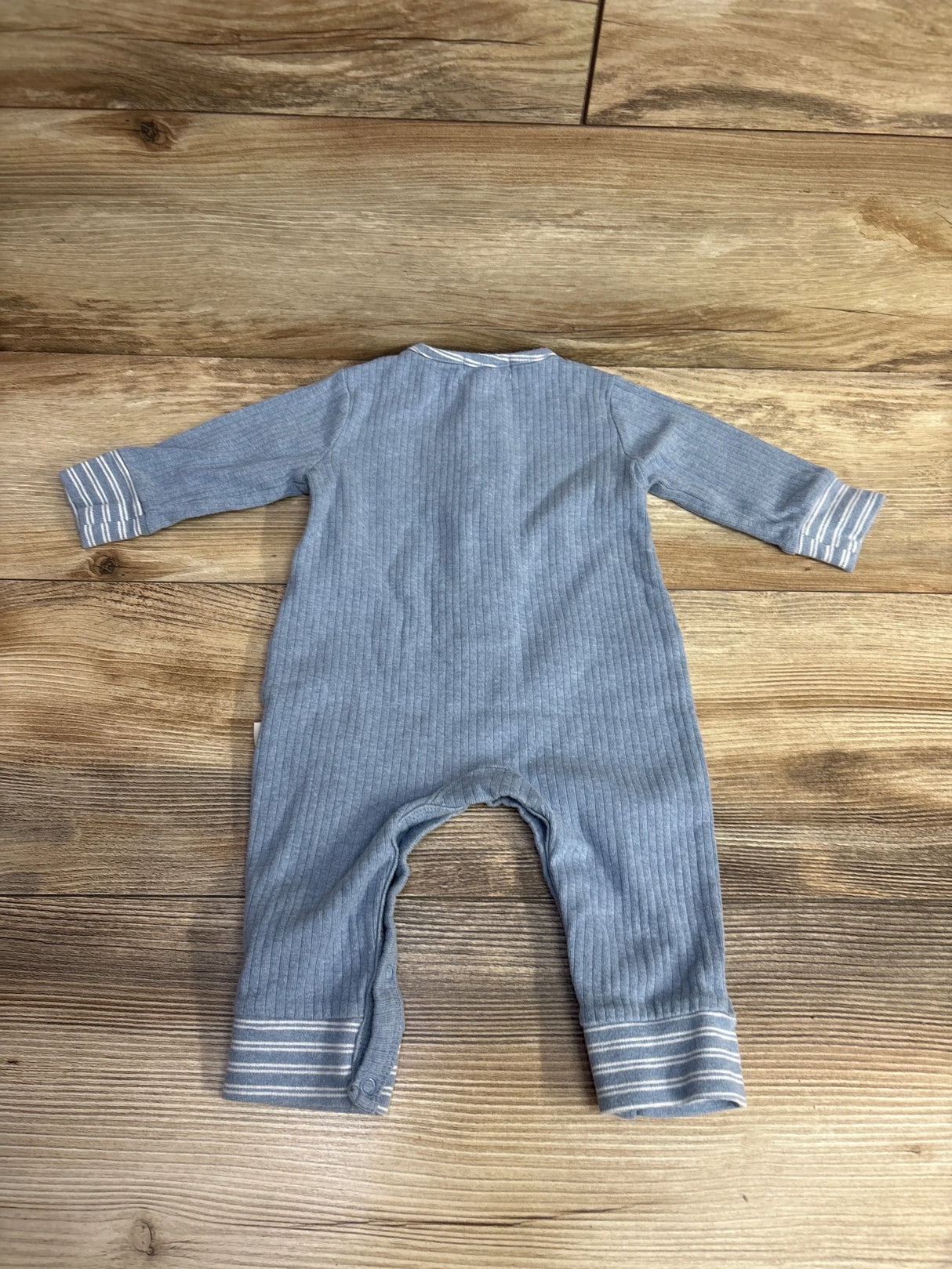 Gray ribbed baby romper with striped cuffs on wood floor, long sleeves, snap legs