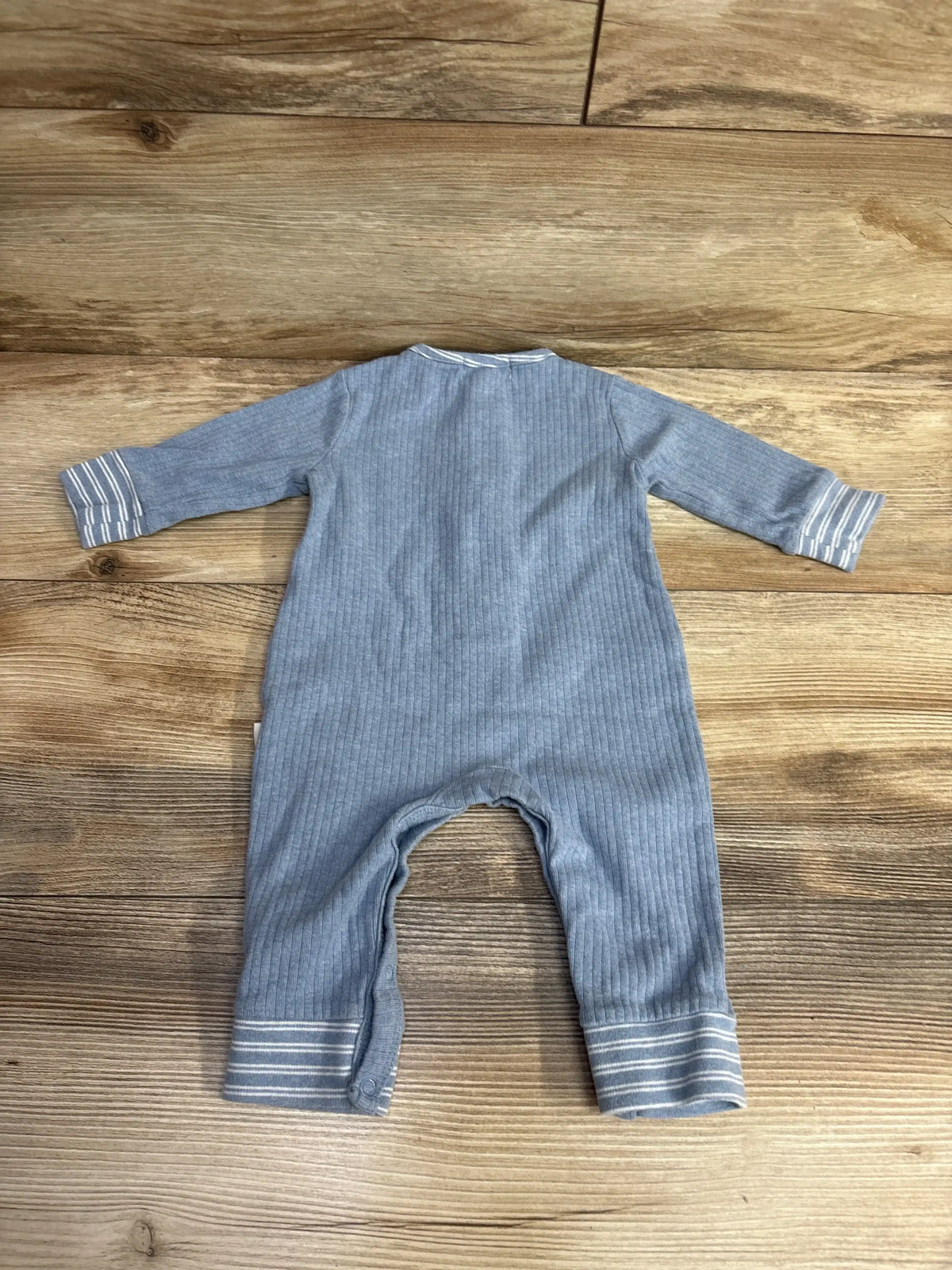 Back view of Rabbit + Bear ribbed coverall in light blue showcasing long sleeves, fold-over striped cuffs and snap-leg closures on wood floor