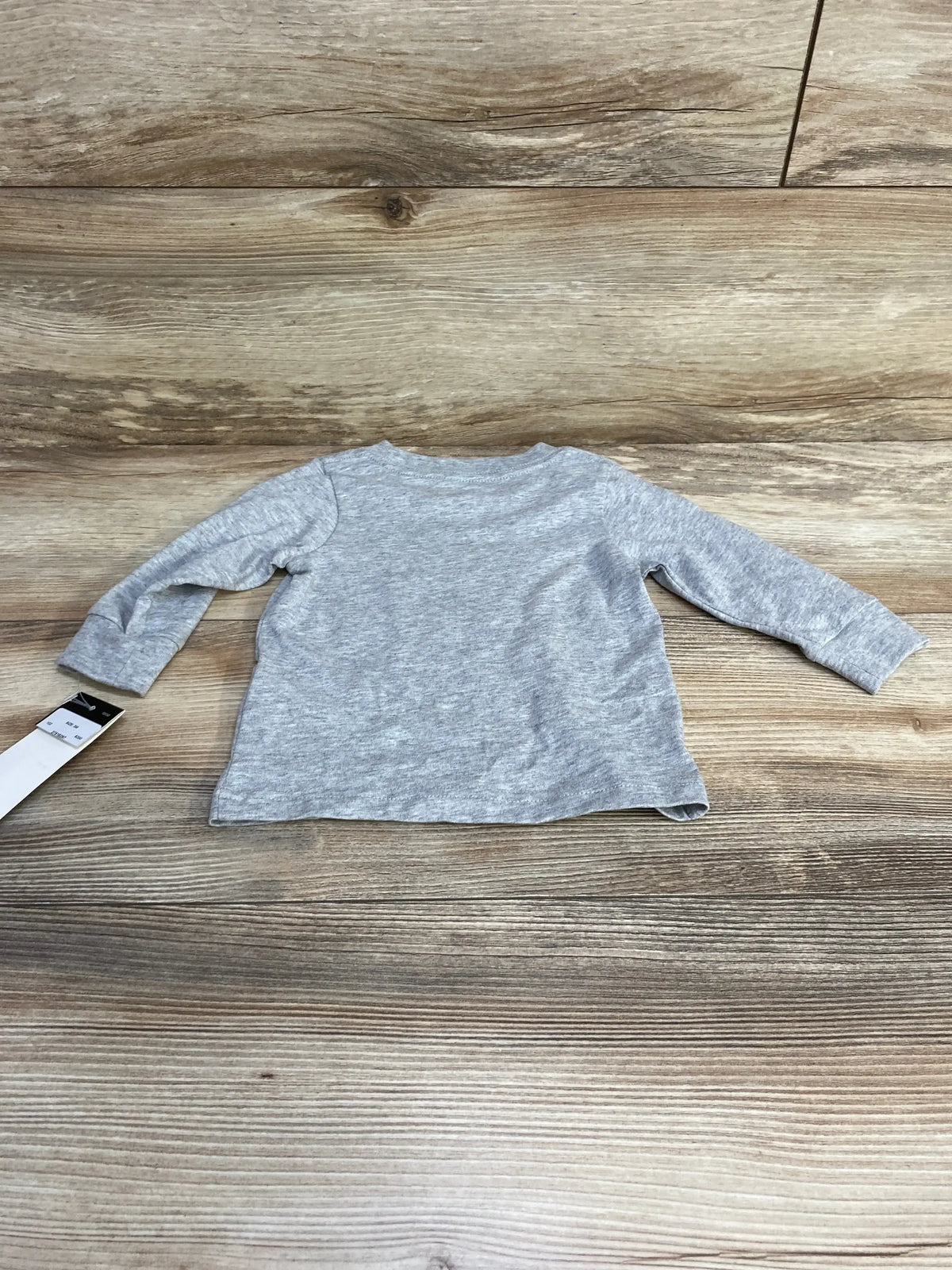 Back view of grey Adidas long-sleeve baby shirt showing crew neckline and heather fabric on wood plank background, size 3M