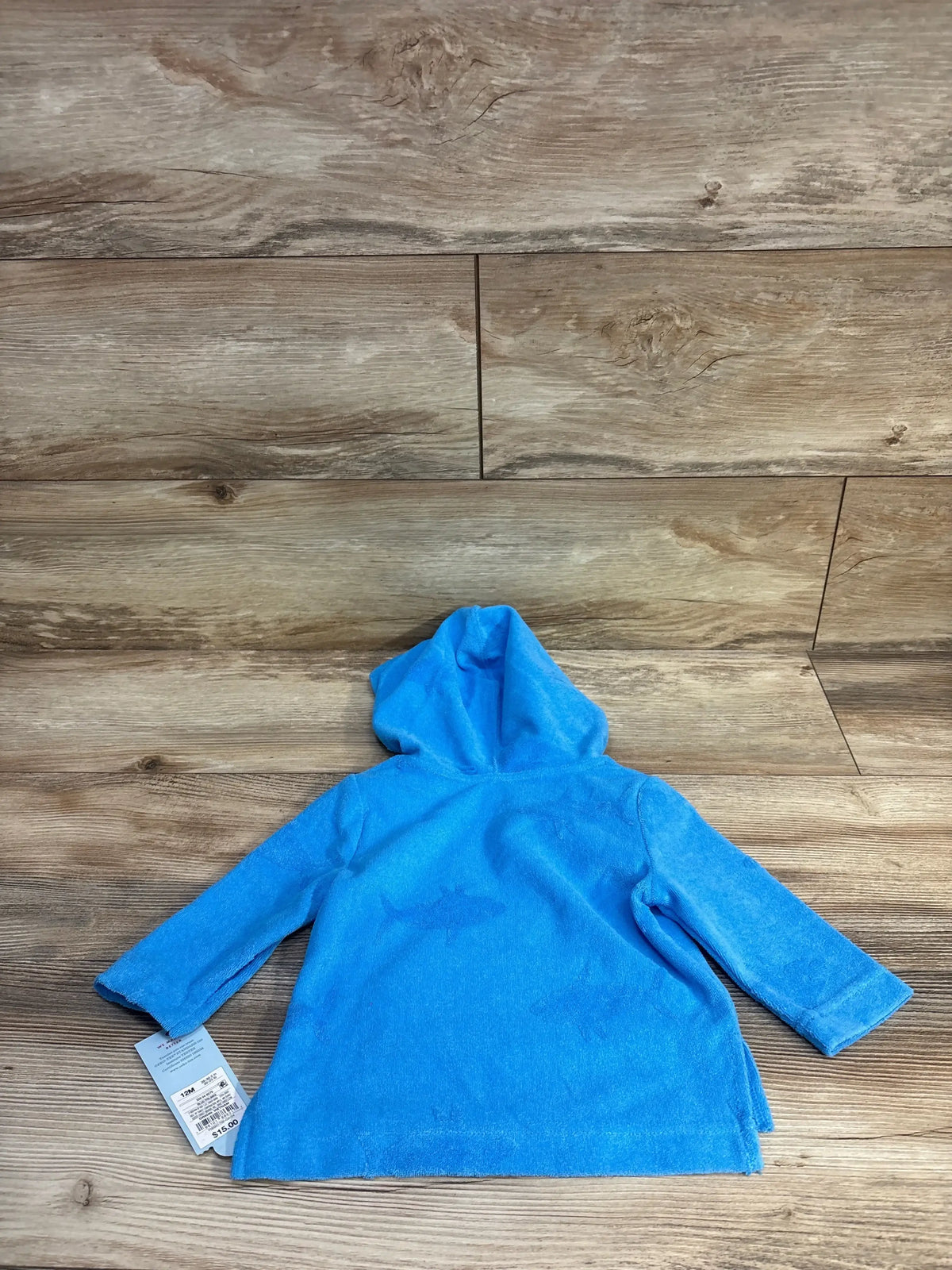 Back view of blue Cat & Jack hooded swim cover-up with shark print and terry texture, size 12M, on wooden background