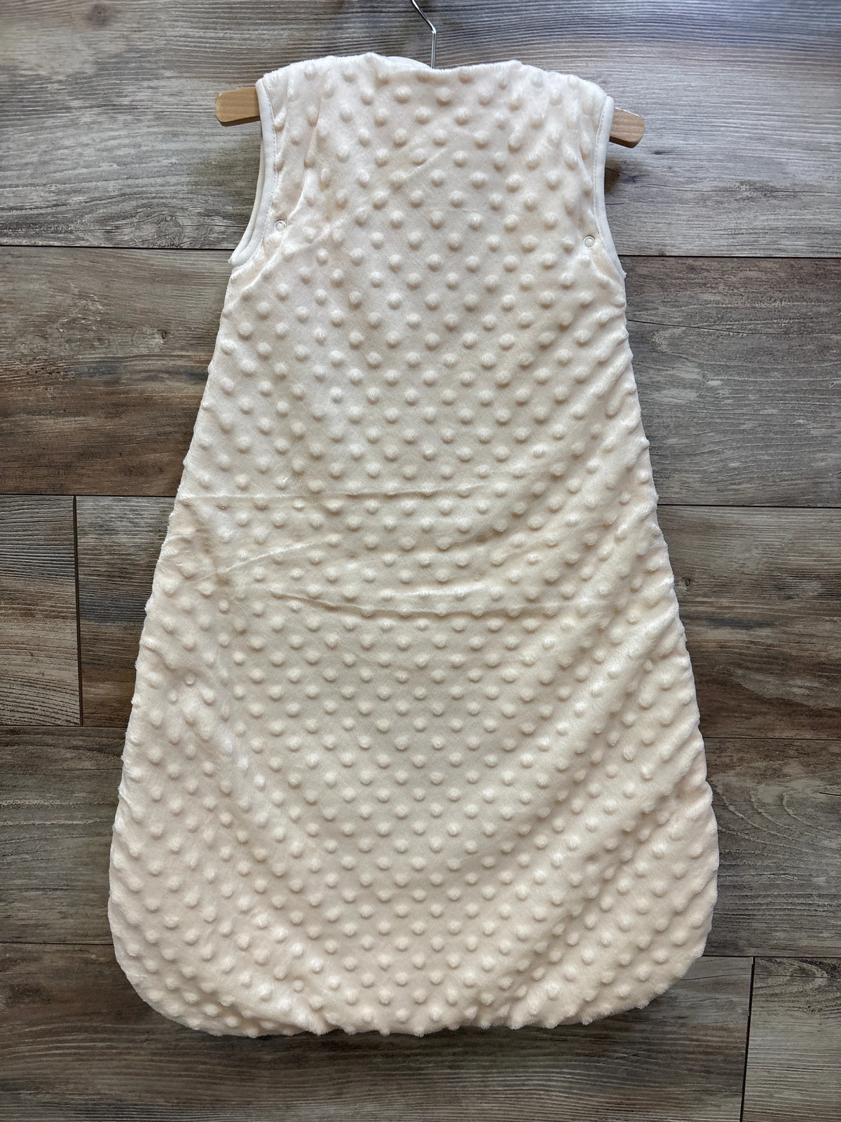 BabyInABag yellow plush minky dot sleep sack hanging on a wooden hanger against a wood wall