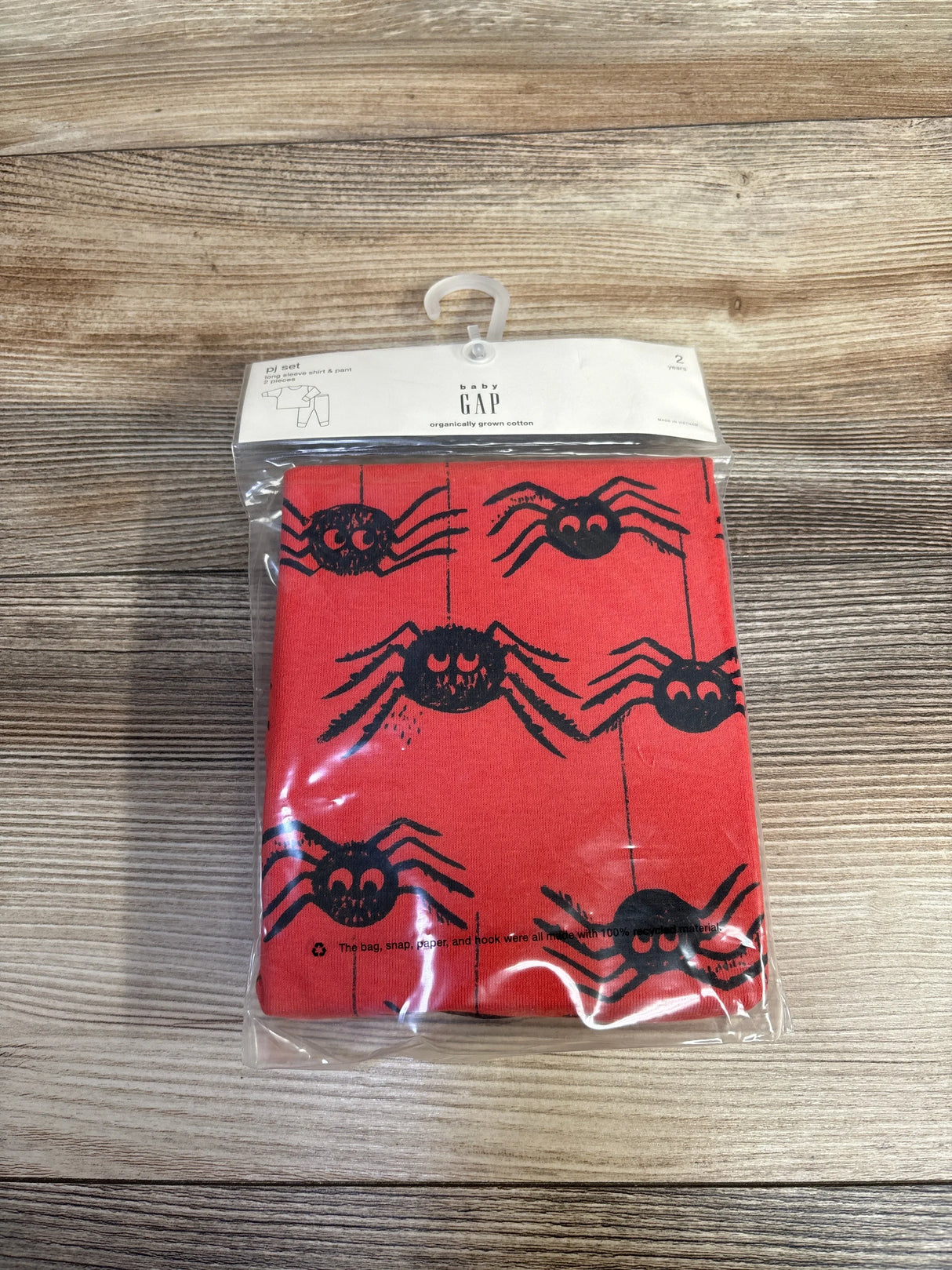 Baby Gap red cotton pajama set with black spider print, packaged on wood surface
