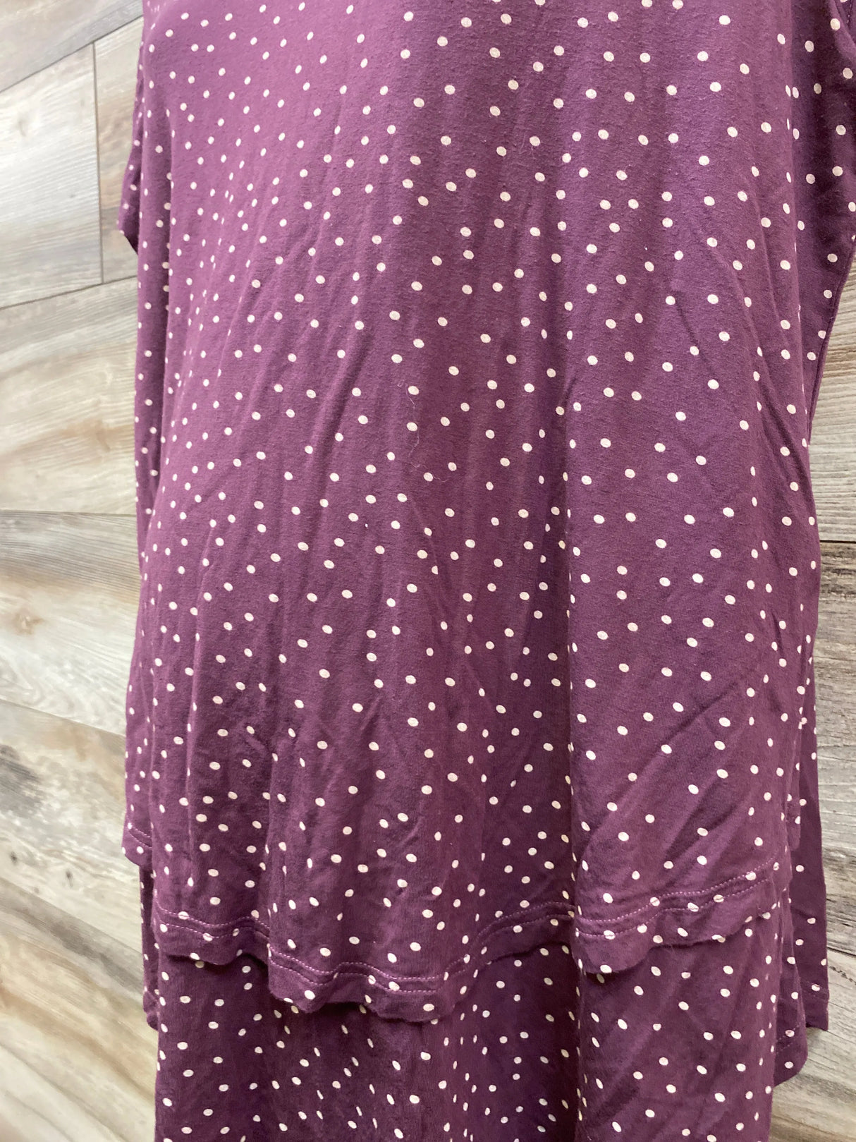 Purple polka dot dress with layered hem against wood background