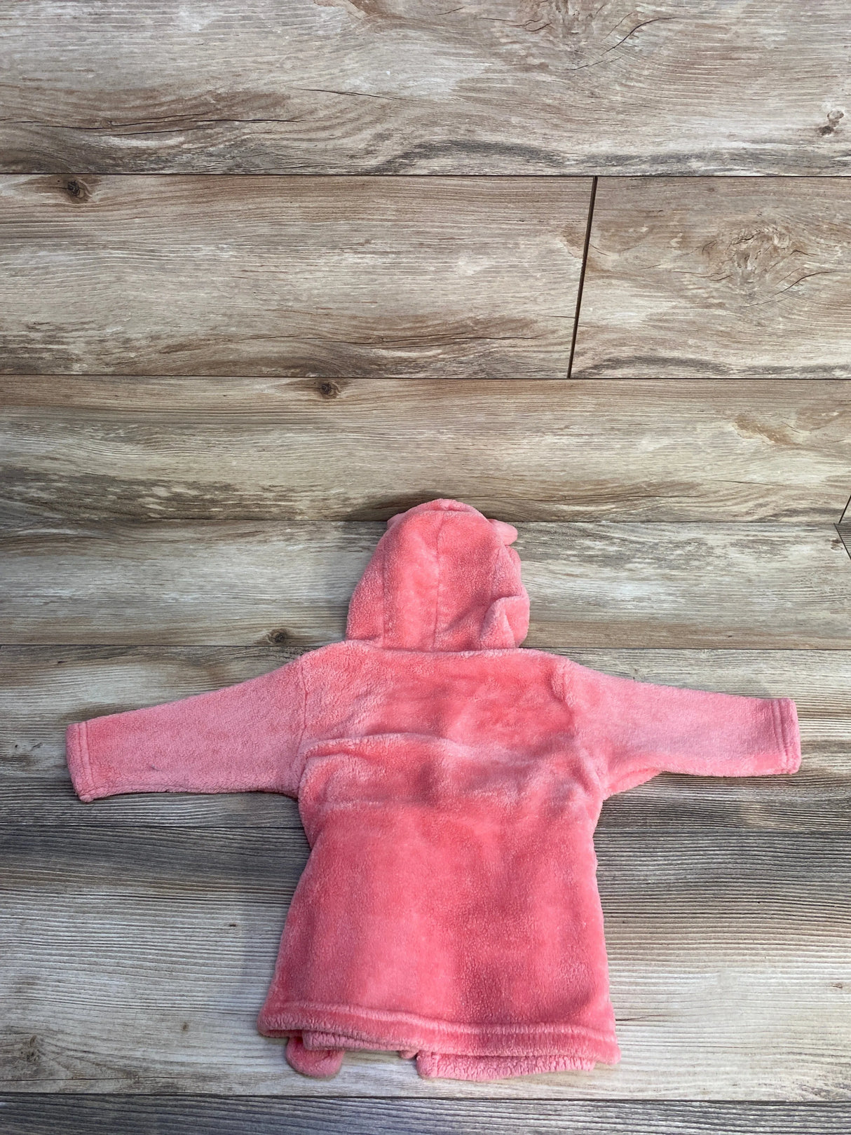 Pink plush baby hooded jacket with bear ears on wood floor