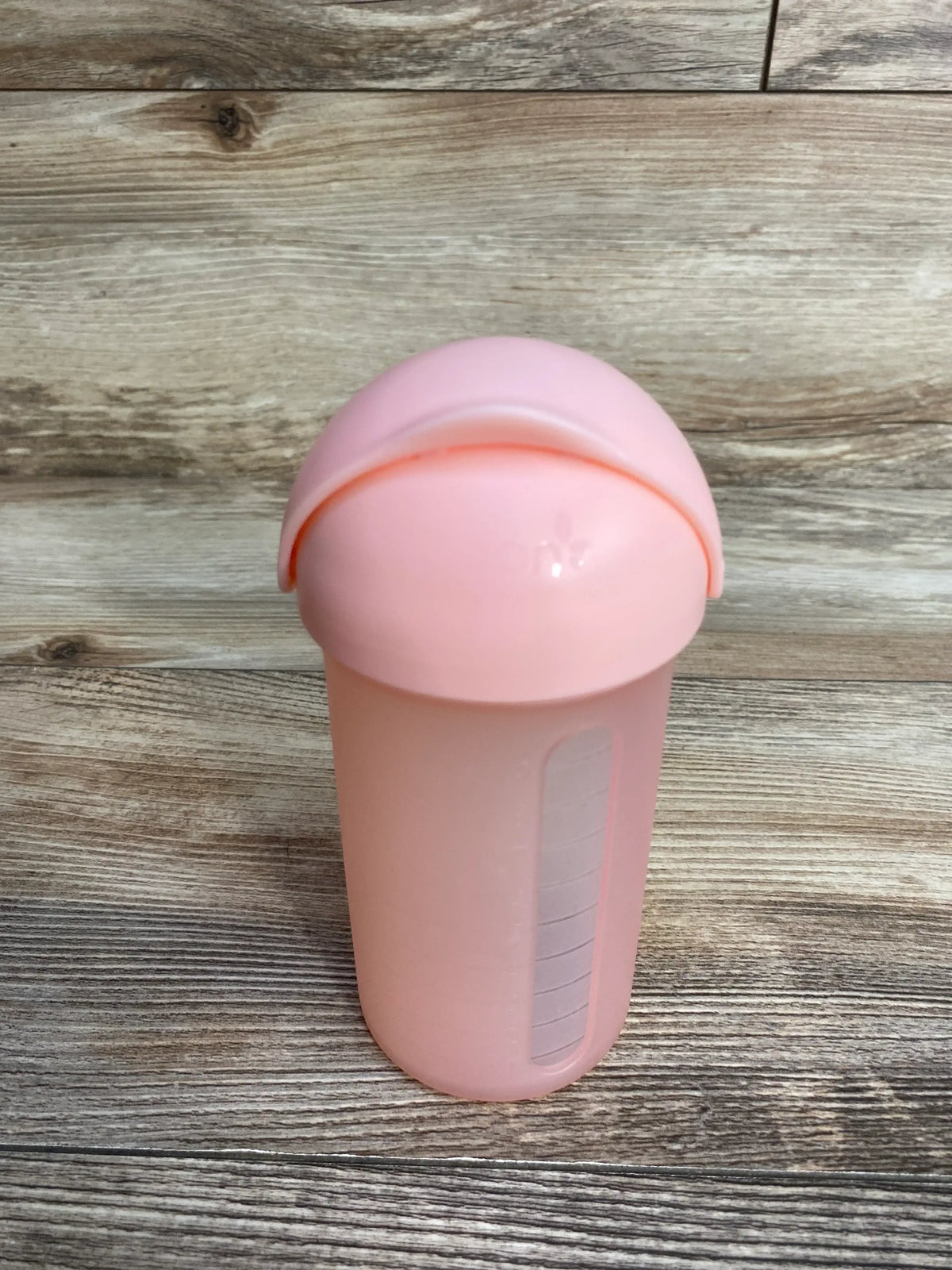 Front view of Boon Swig silicone straw cup showcasing pink 9oz bottle with flip lid and side measurement window on wood plank floor