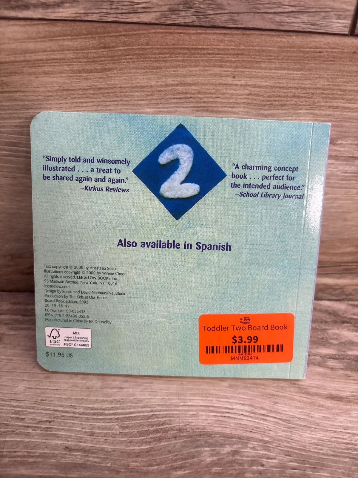 Back cover of 'Toddler Two' board book with reviews, price sticker, and wood background.