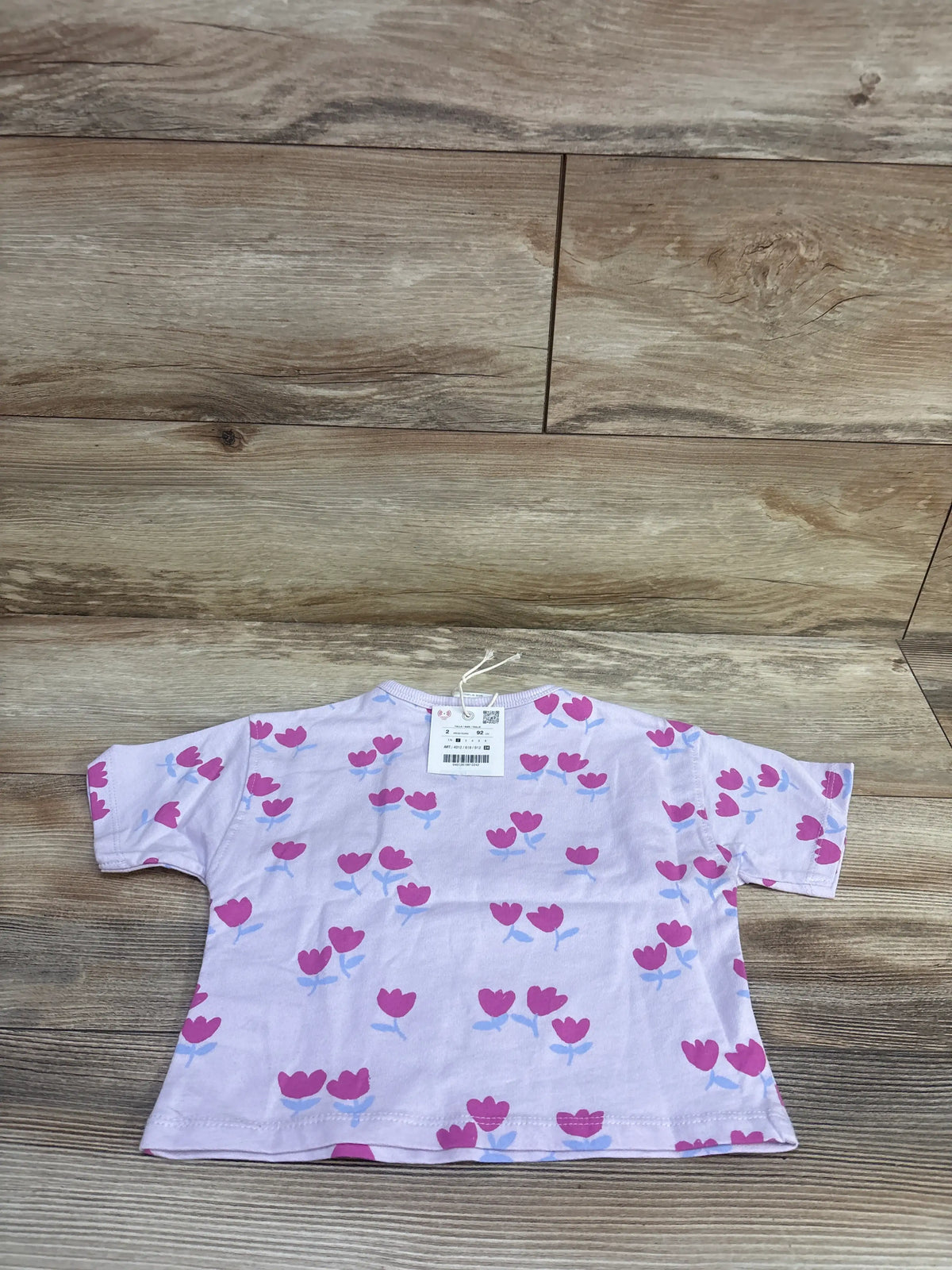 Front view of a lilac Zara tulip shirt in size 2T showcasing short sleeves and tulip print on a wood-look background